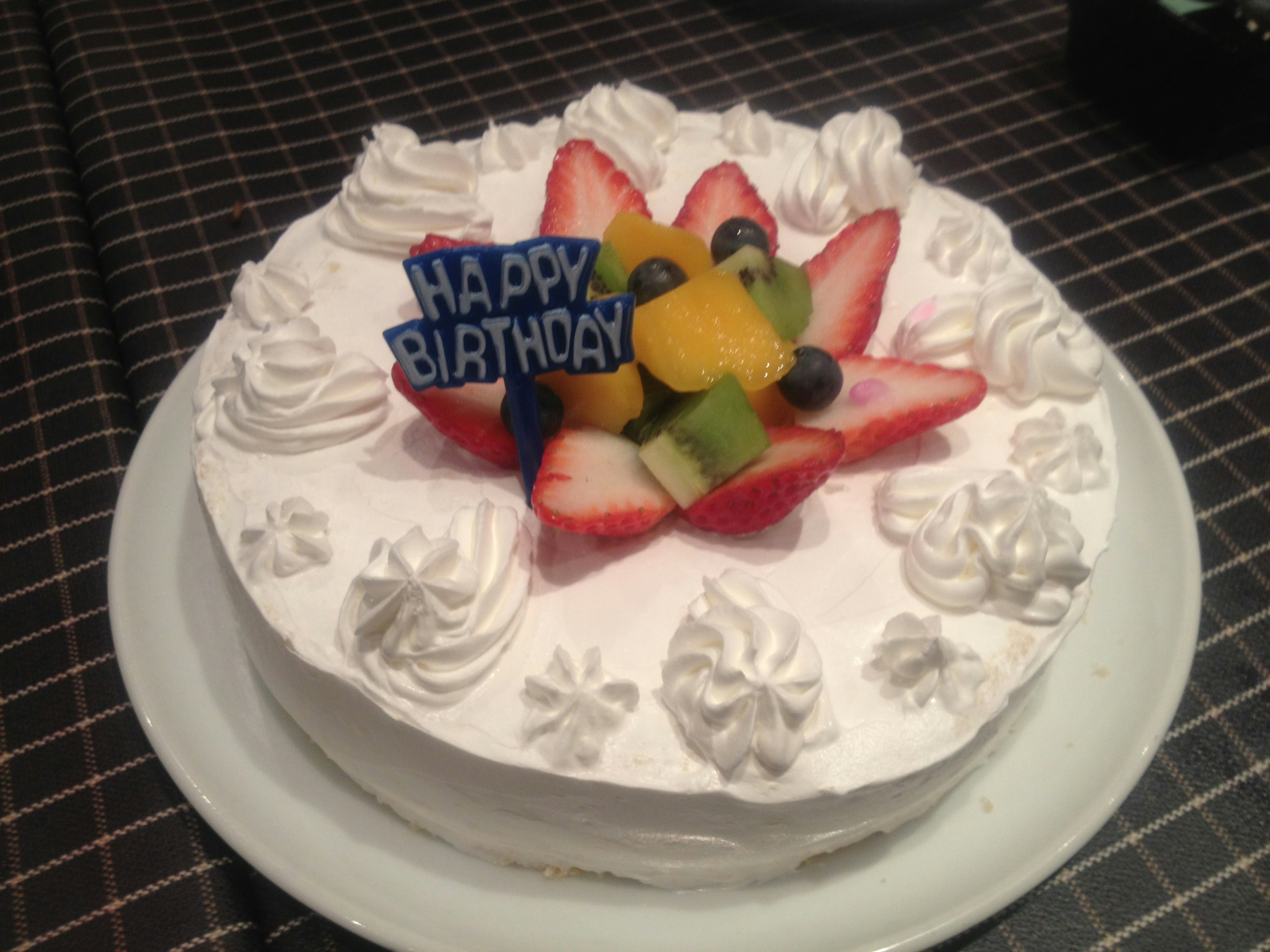 Pastel de cumpleaños decorado con crema batida y frutas frescas