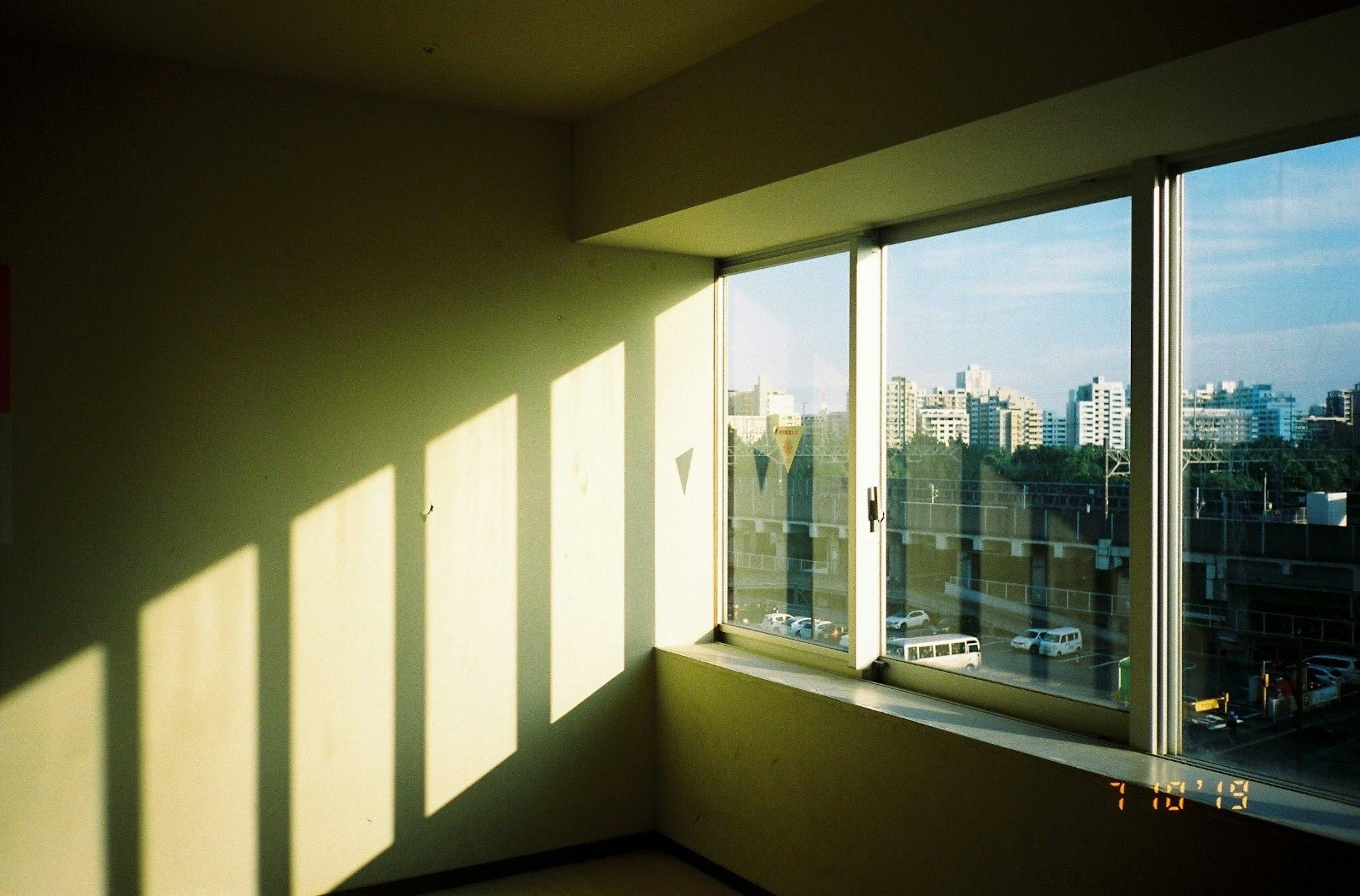 Bright sunlight streaming through a window in a room with a city view