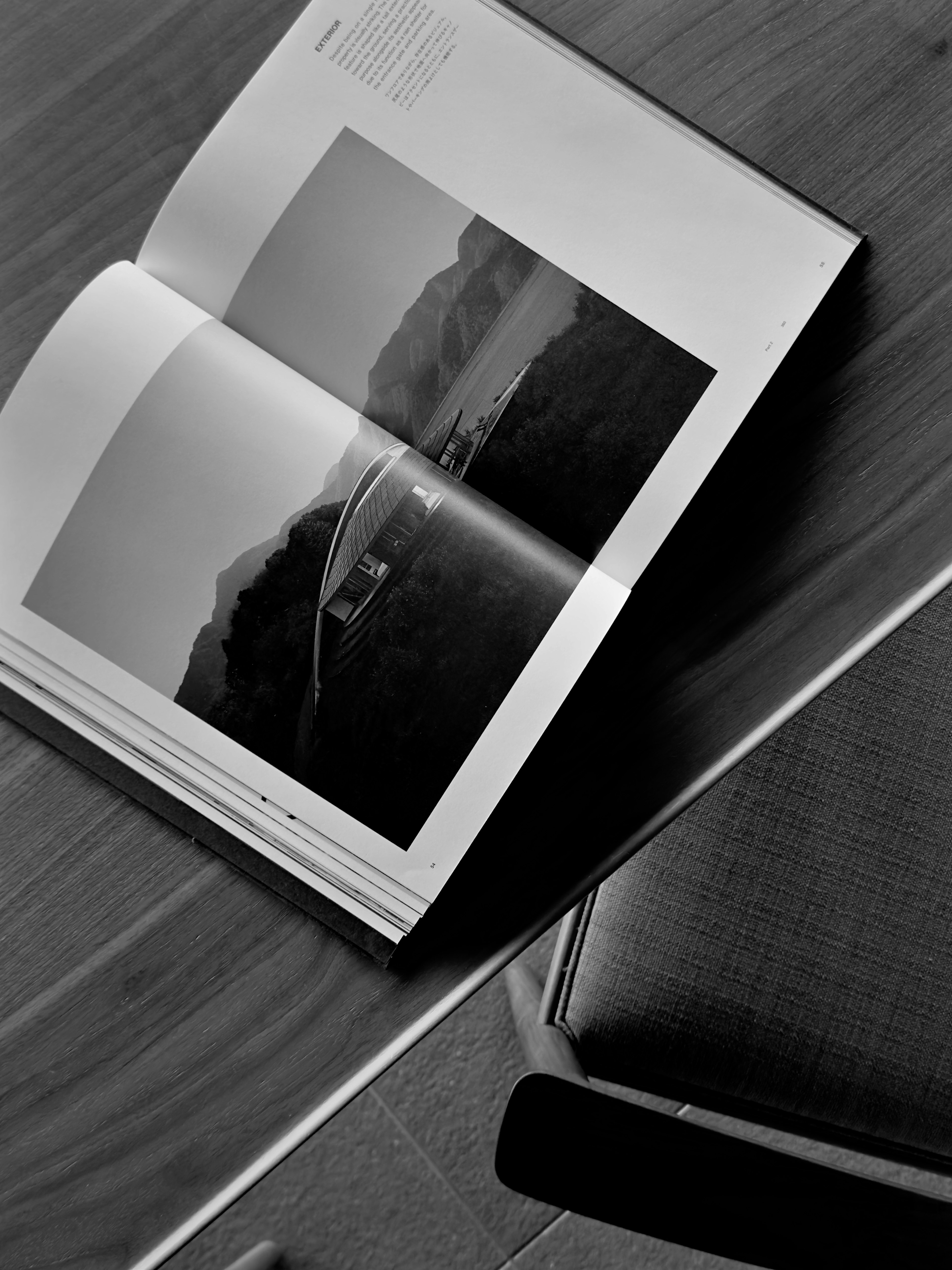 Un magazine en noir et blanc ouvert sur une table en bois montrant une belle photo de paysage