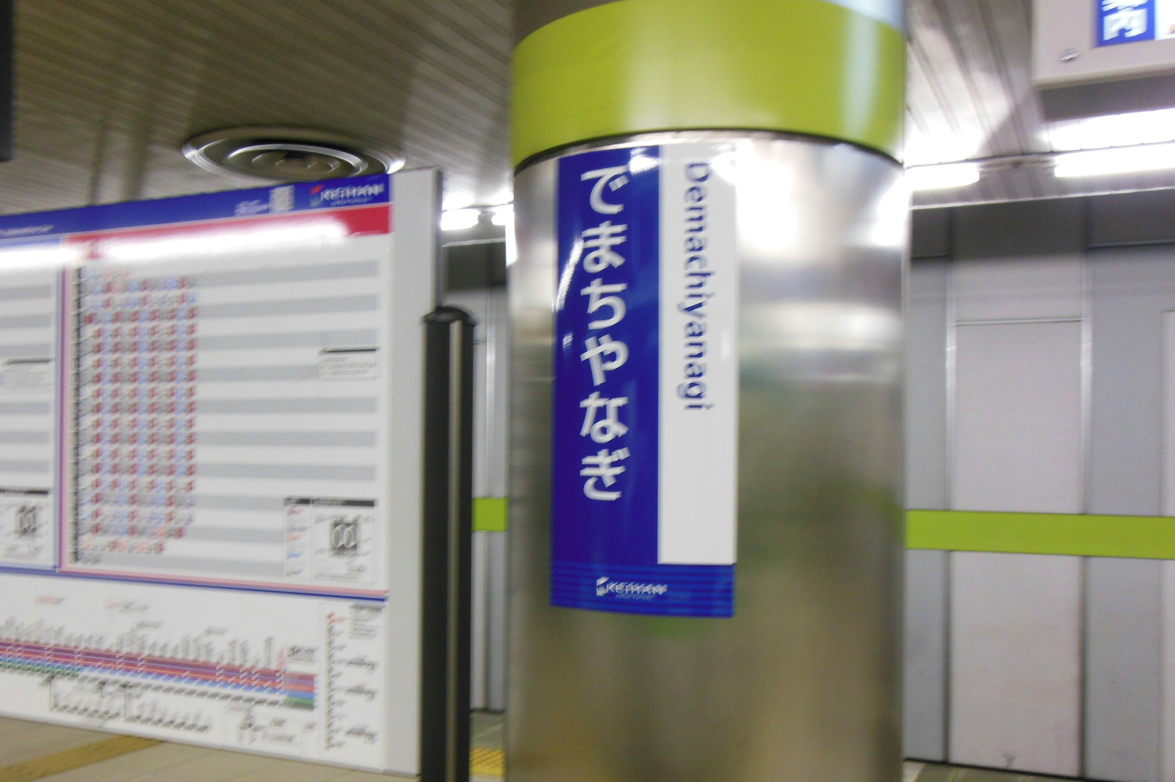 駅の柱に取り付けられた案内看板で、行き先と時刻表が表示されている