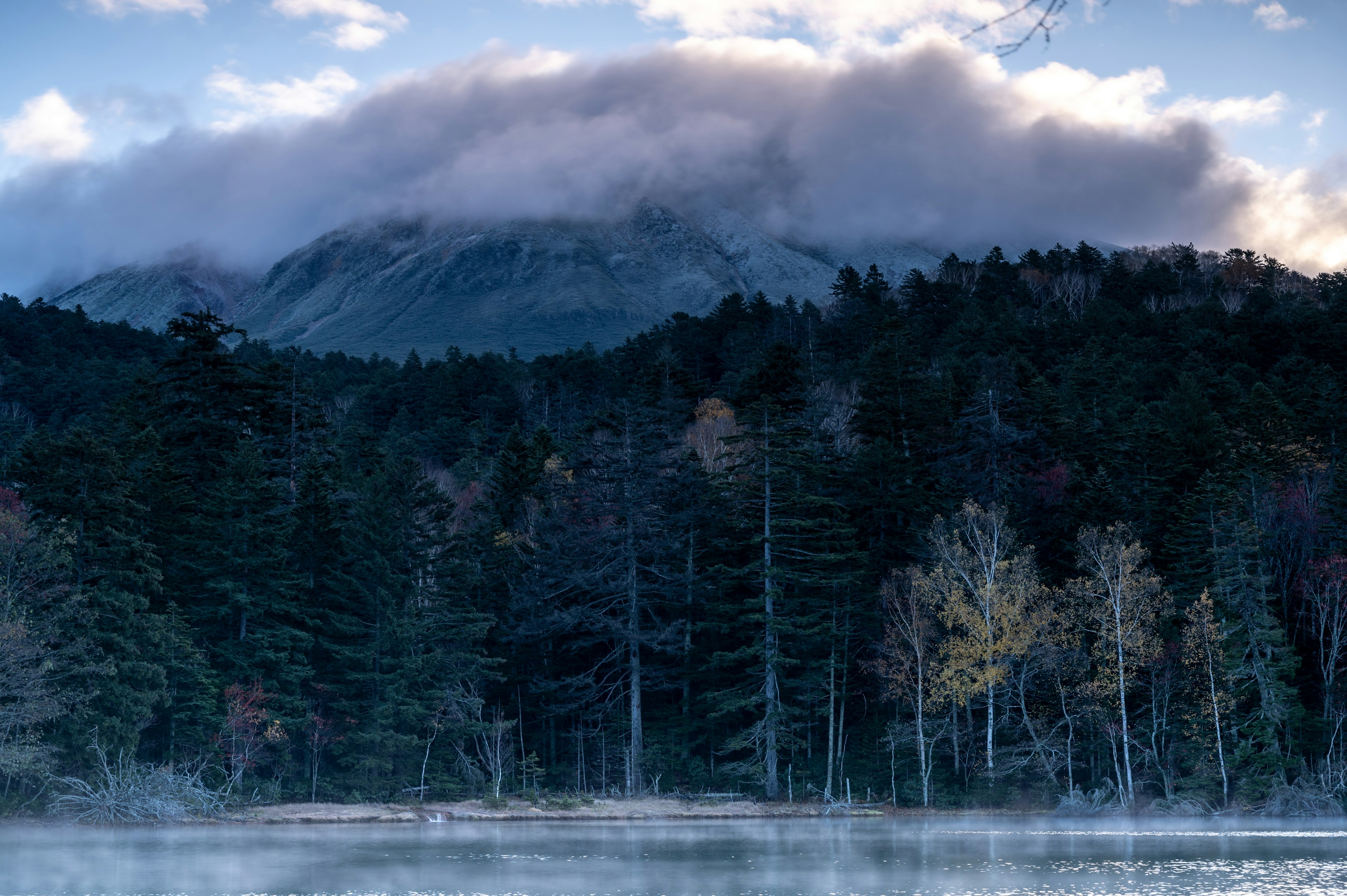 Fog-covered mountain with a serene lake and forest