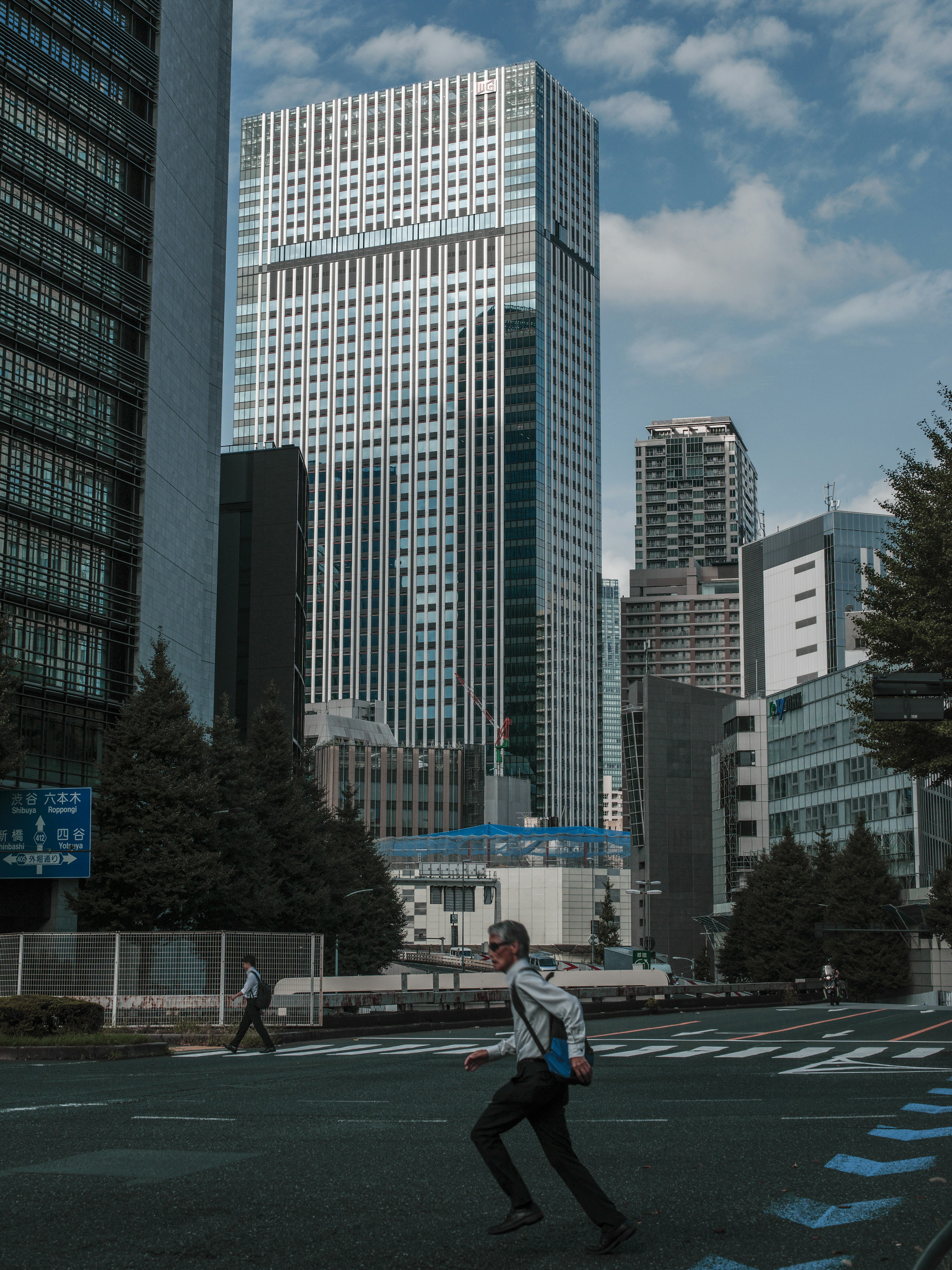 Paisaje urbano con personas caminando entre rascacielos bajo un cielo despejado