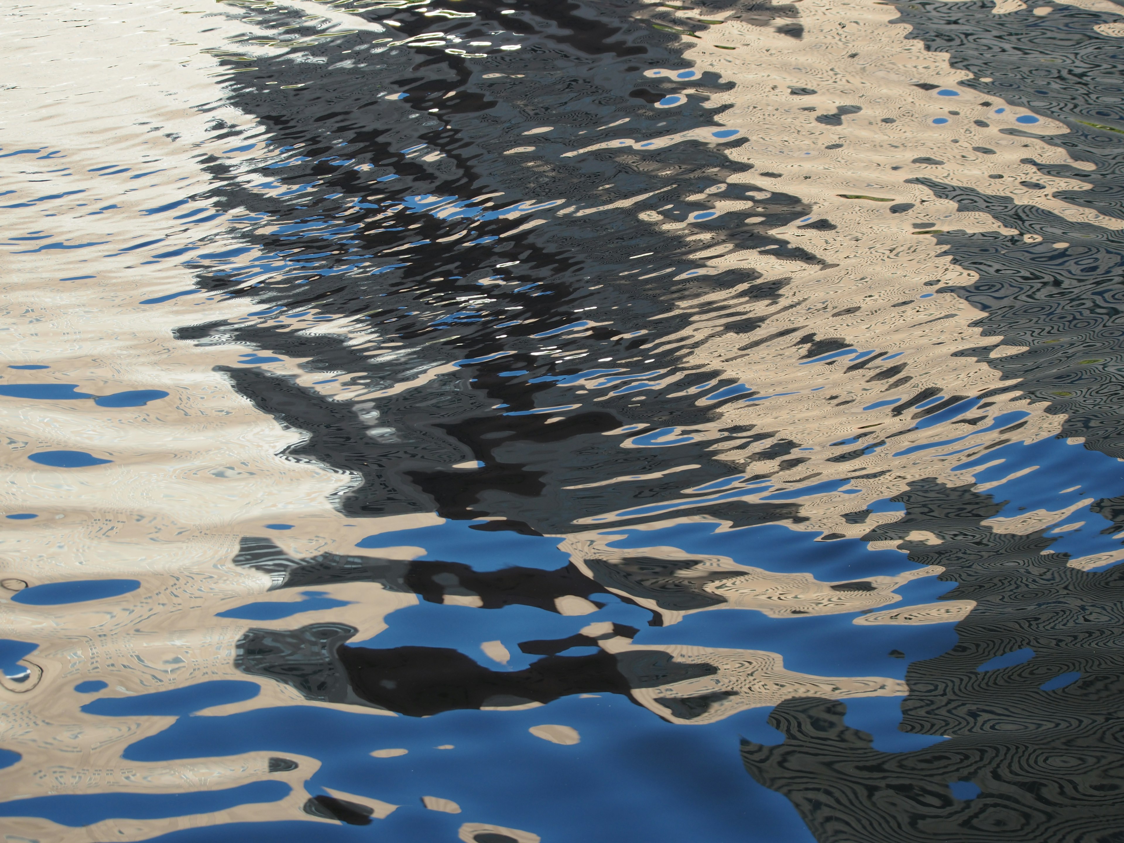 Rippling water surface reflecting shadows and colors