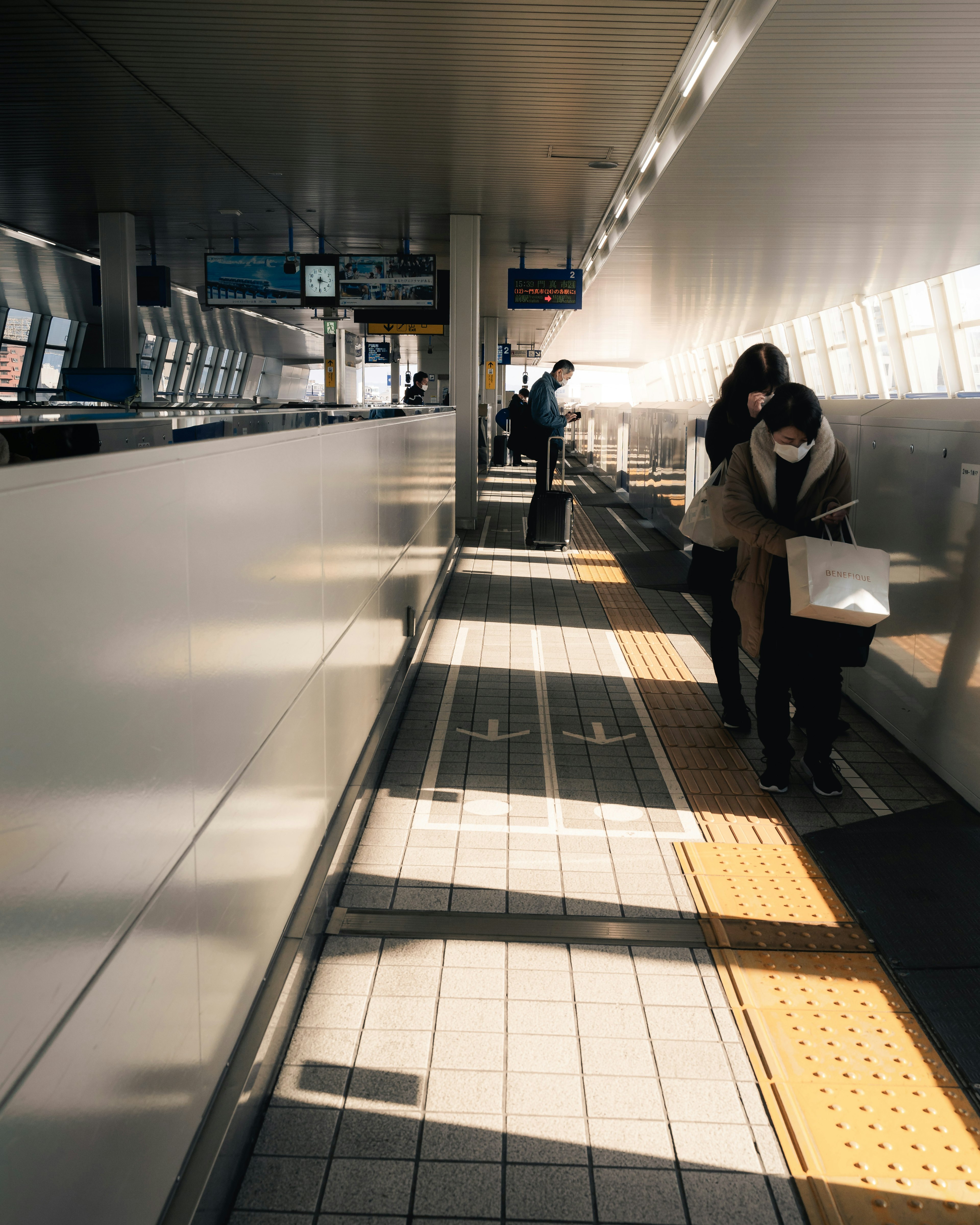 People moving on a train platform with bright light and shadows