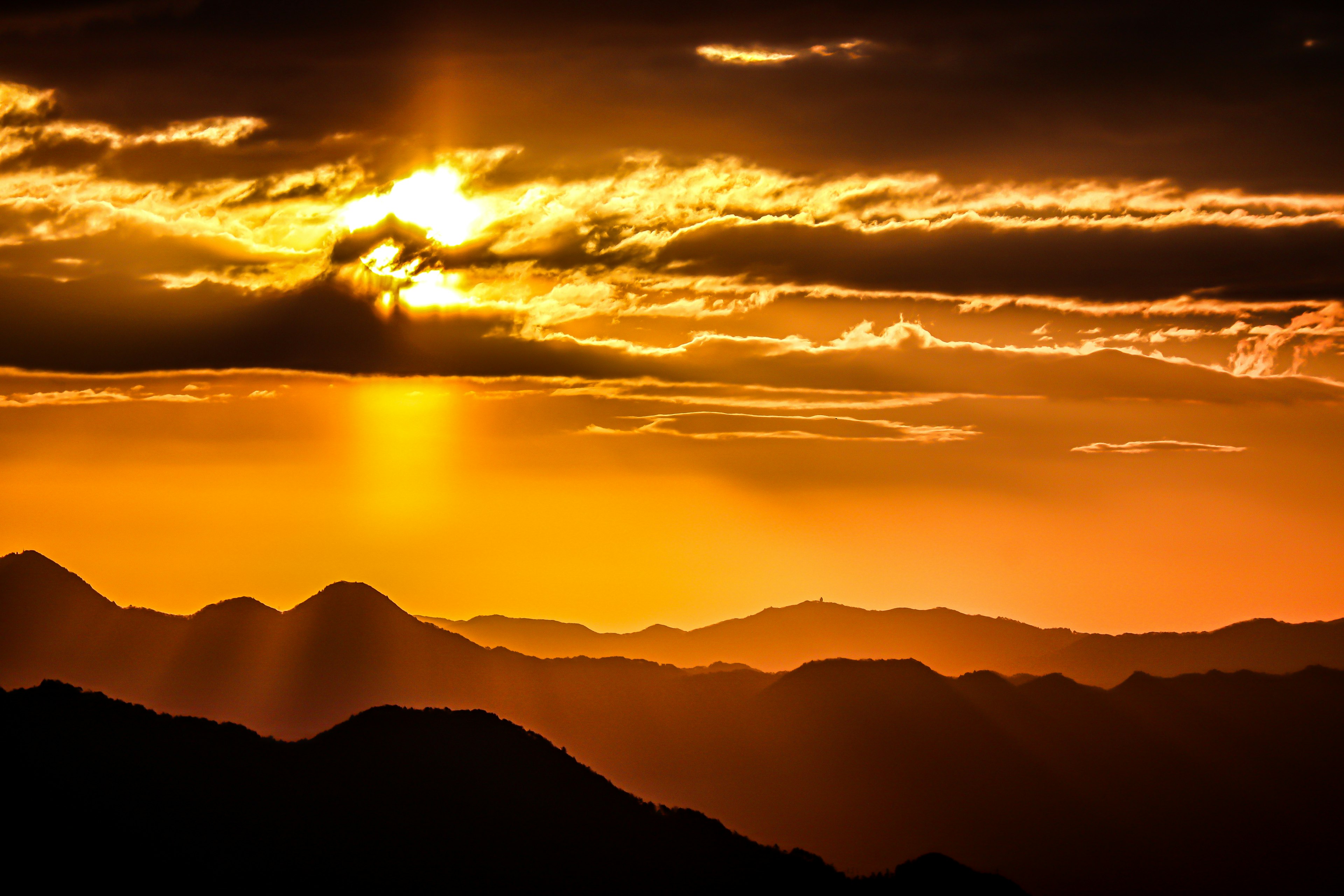 Paysage magnifique avec le coucher de soleil brillants à travers les montagnes