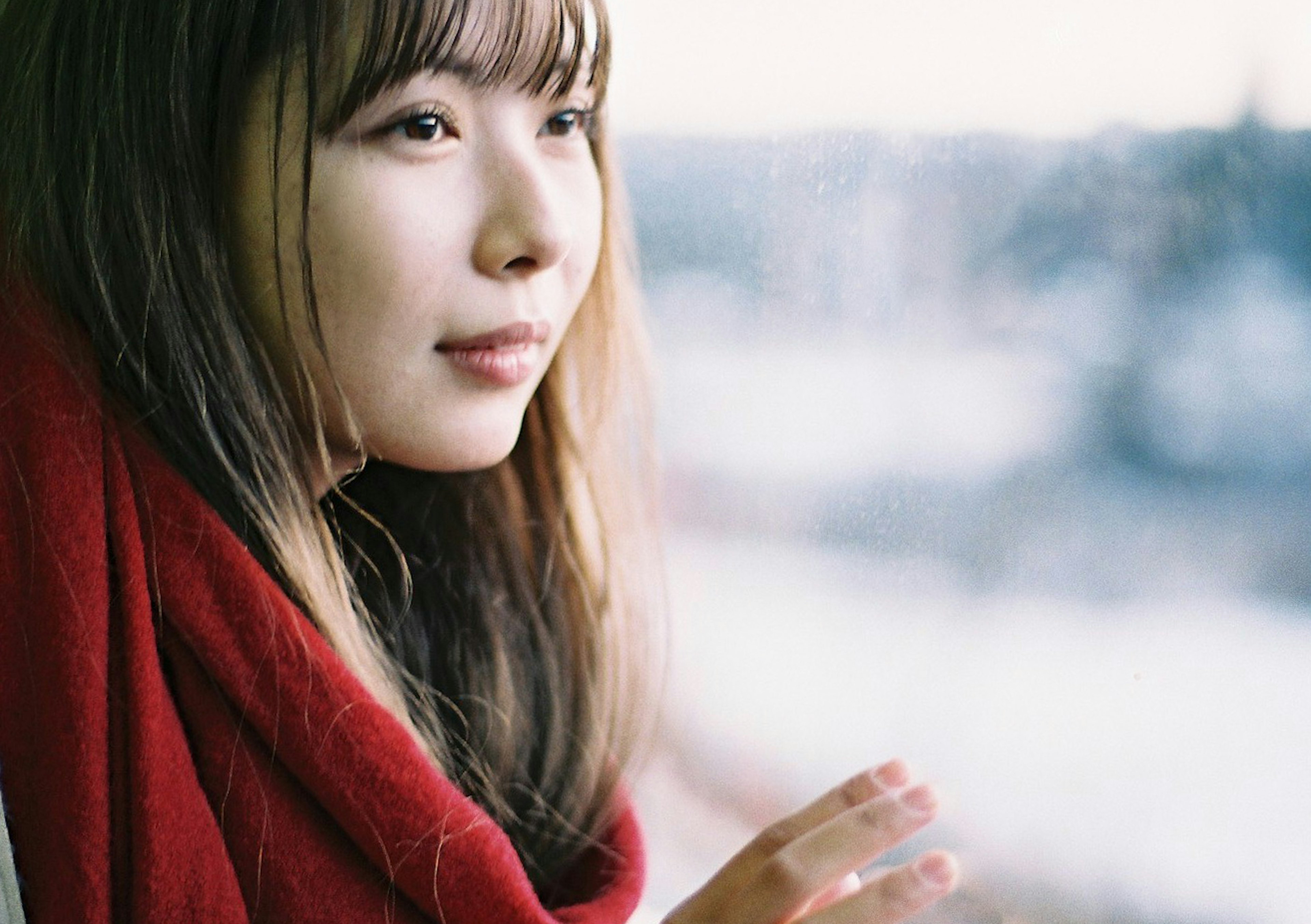 Portrait of a woman gazing out the window wearing a red scarf