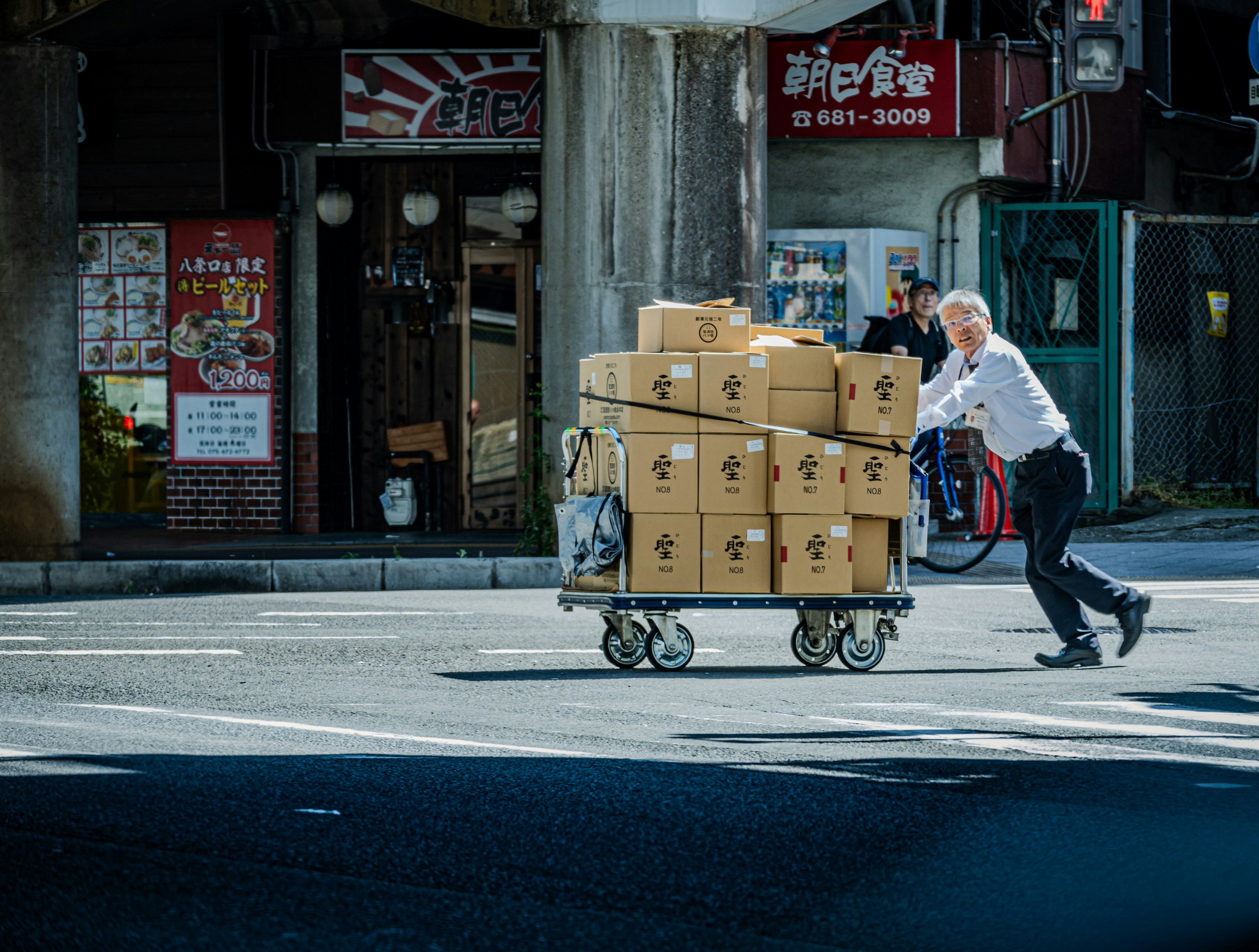 Un homme poussant un chariot chargé de boîtes dans un environnement urbain