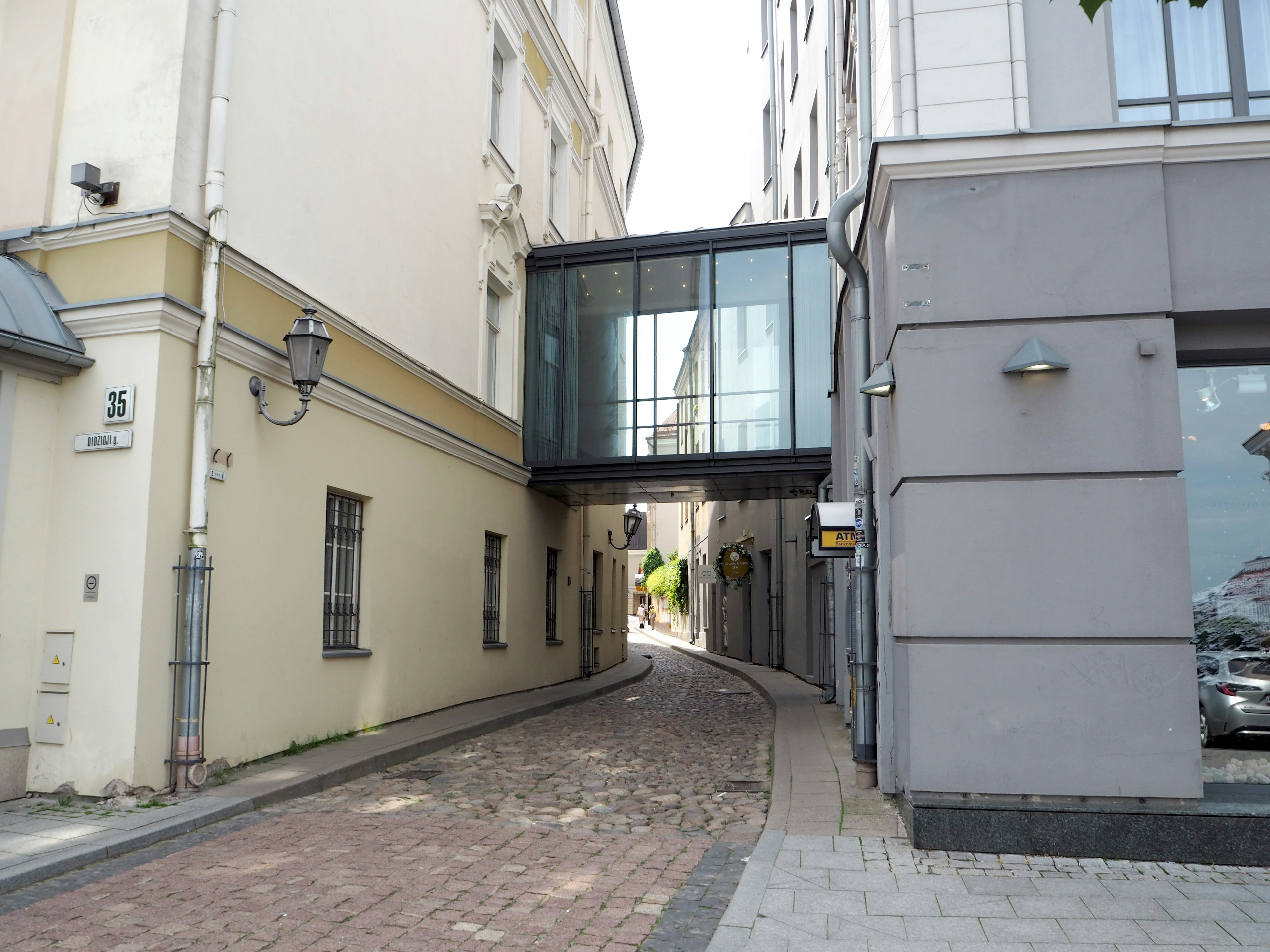 Calle estrecha con un puente de vidrio que conecta dos edificios