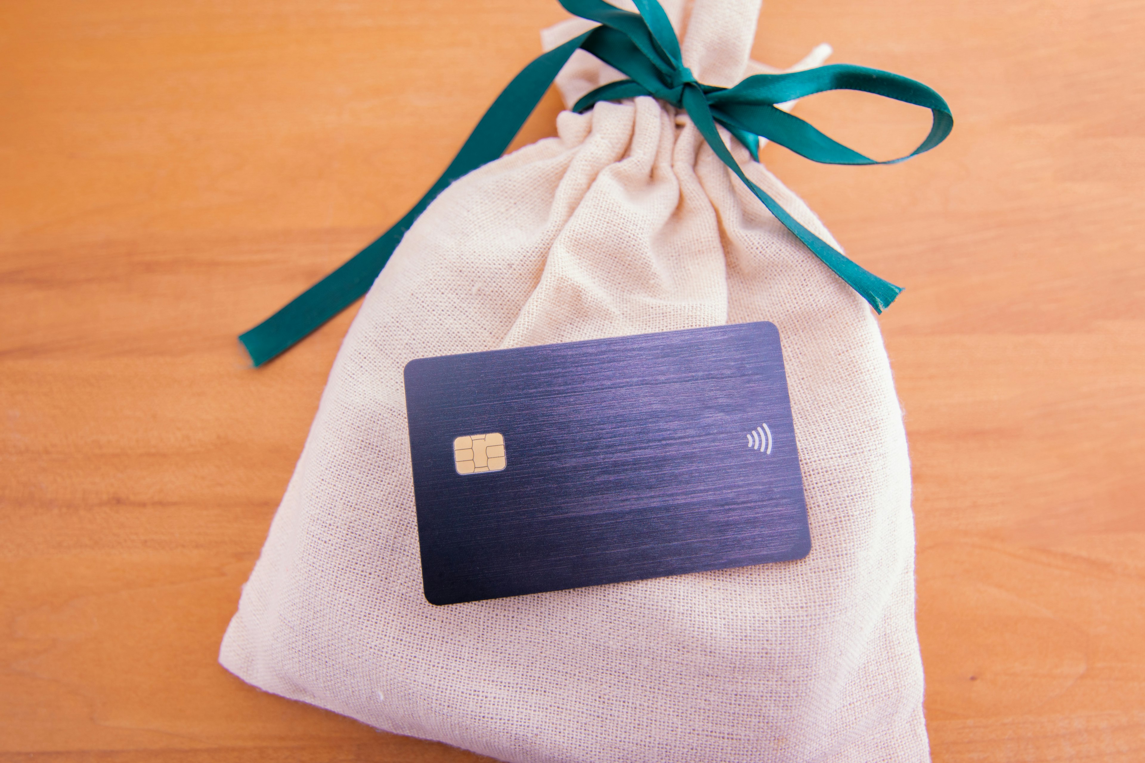 A black card resting on a cream drawstring bag tied with a green ribbon