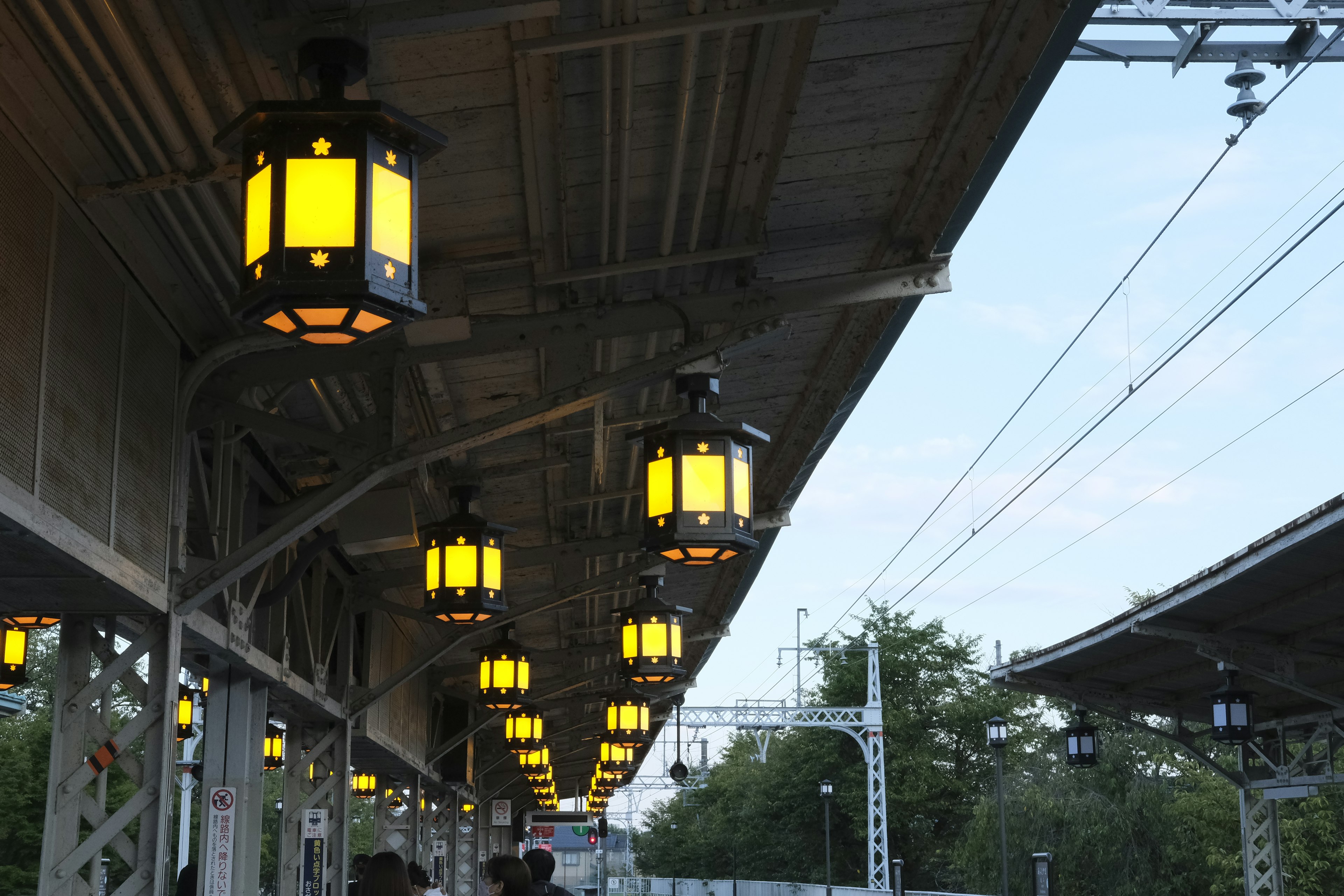 Row of yellow lanterns hanging under a train station roof