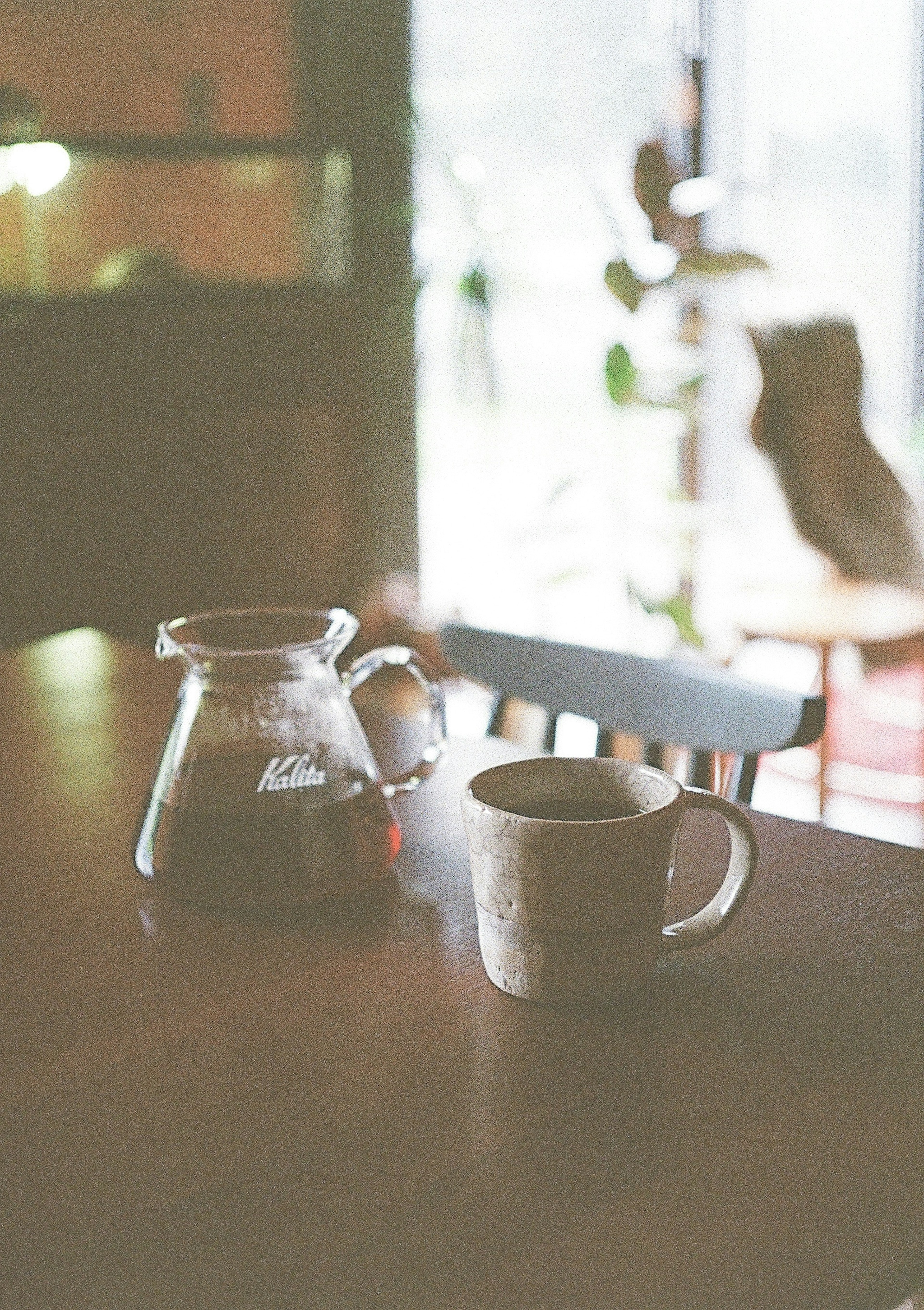 Coffee pot and cup on a wooden table with a cozy background