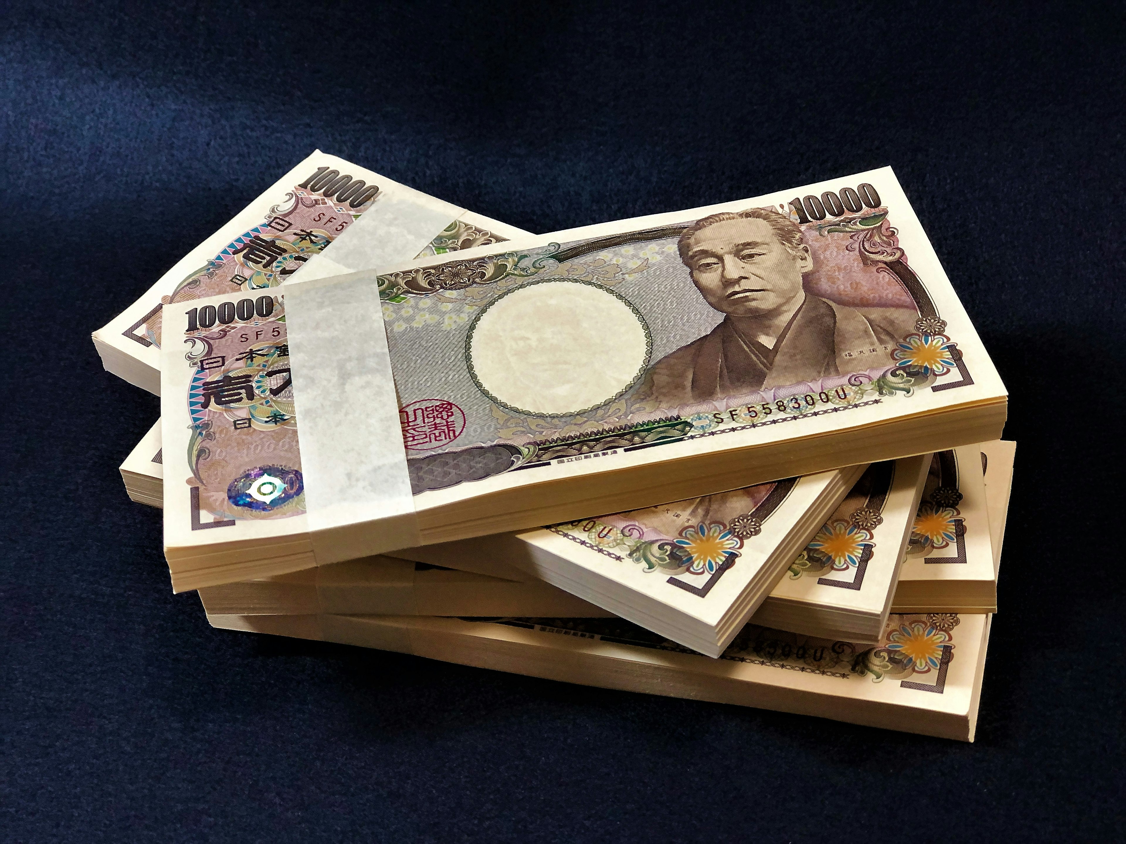 Tumpukan uang 10.000 yen Jepang di latar belakang gelap