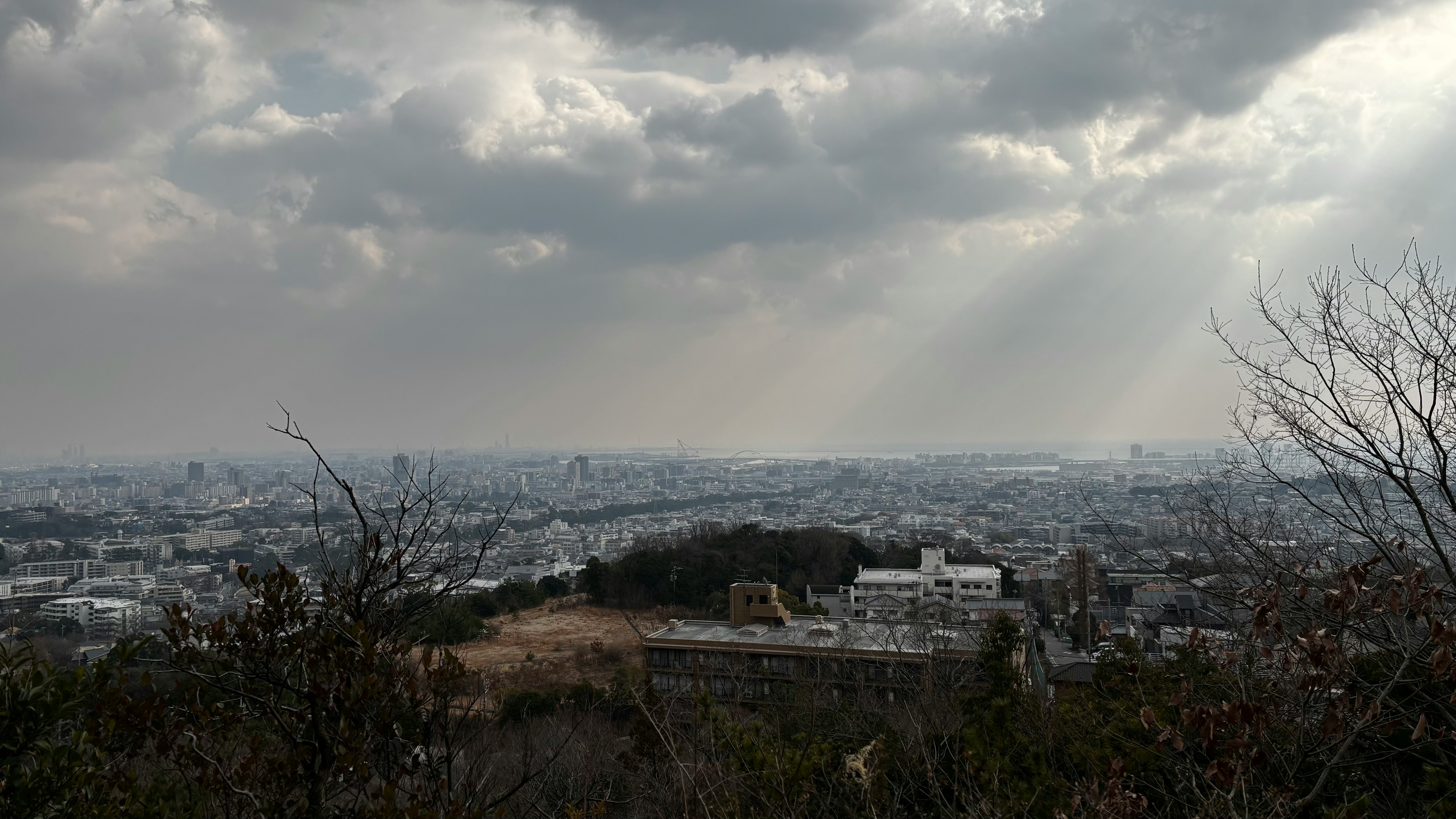 雲に覆われた空の下に広がる都市の風景と山のシルエット