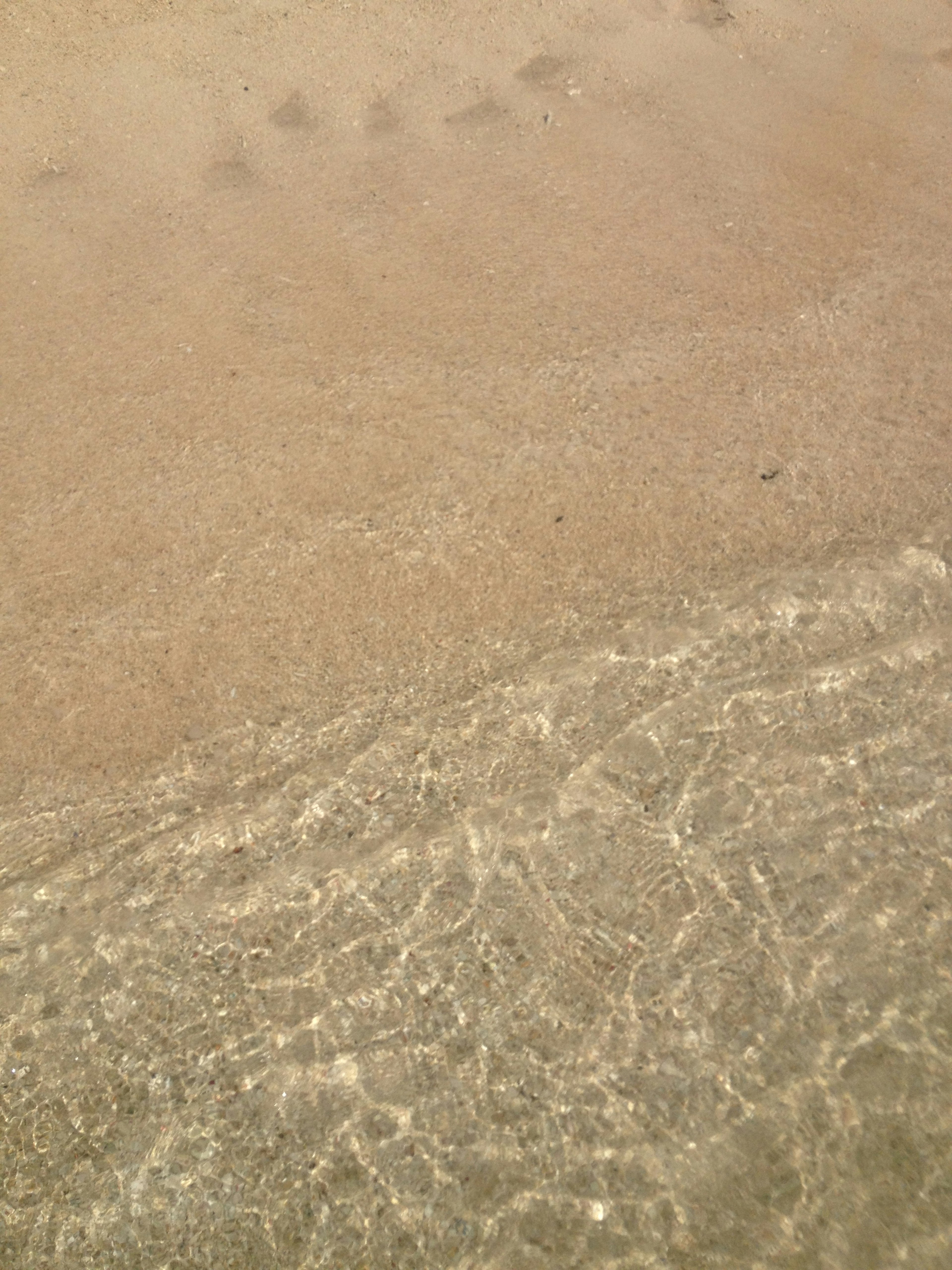 Gambar yang menangkap pertemuan gelombang air dan pantai berpasir