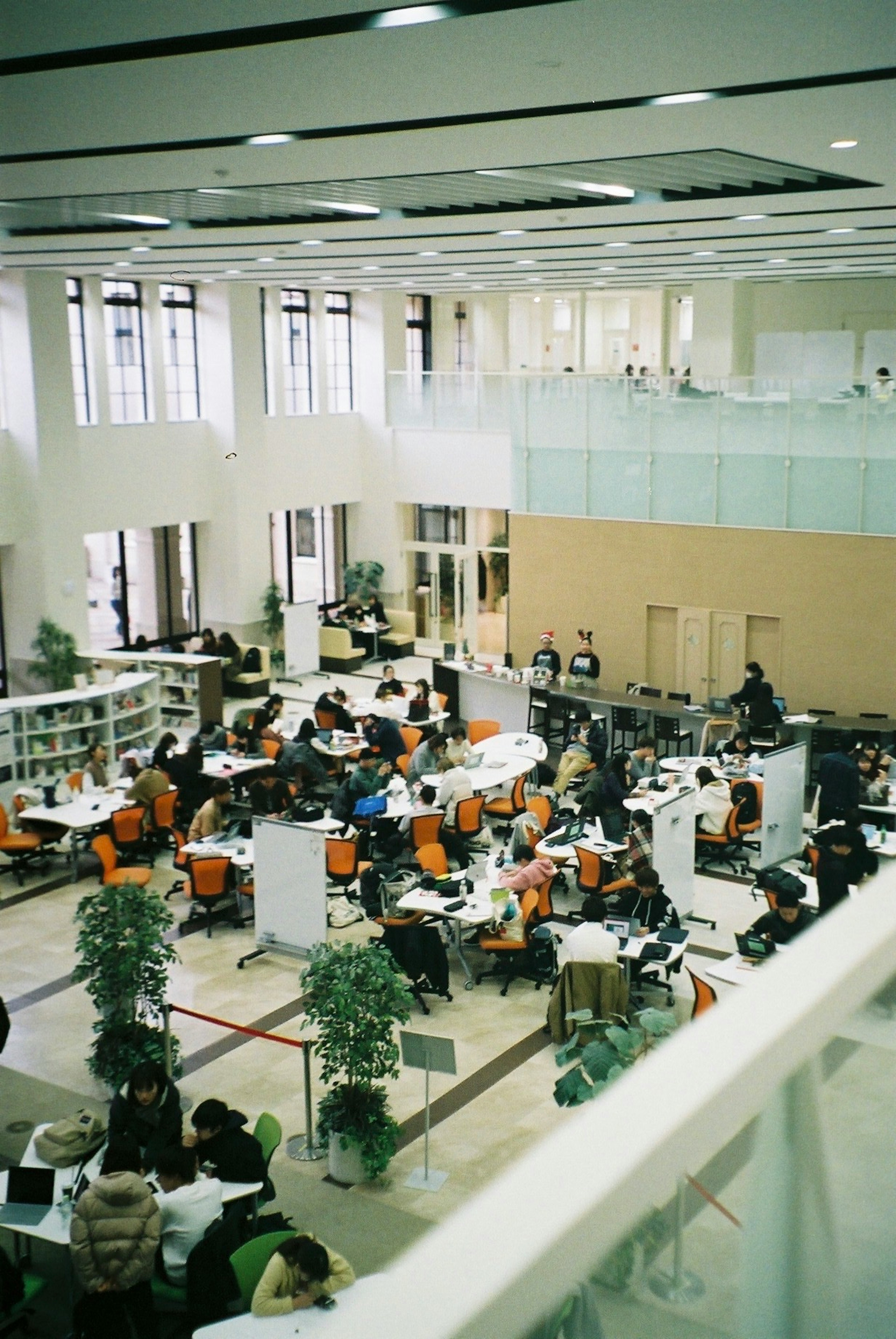 Interno di una biblioteca spaziosa piena di studenti ai tavoli di studio