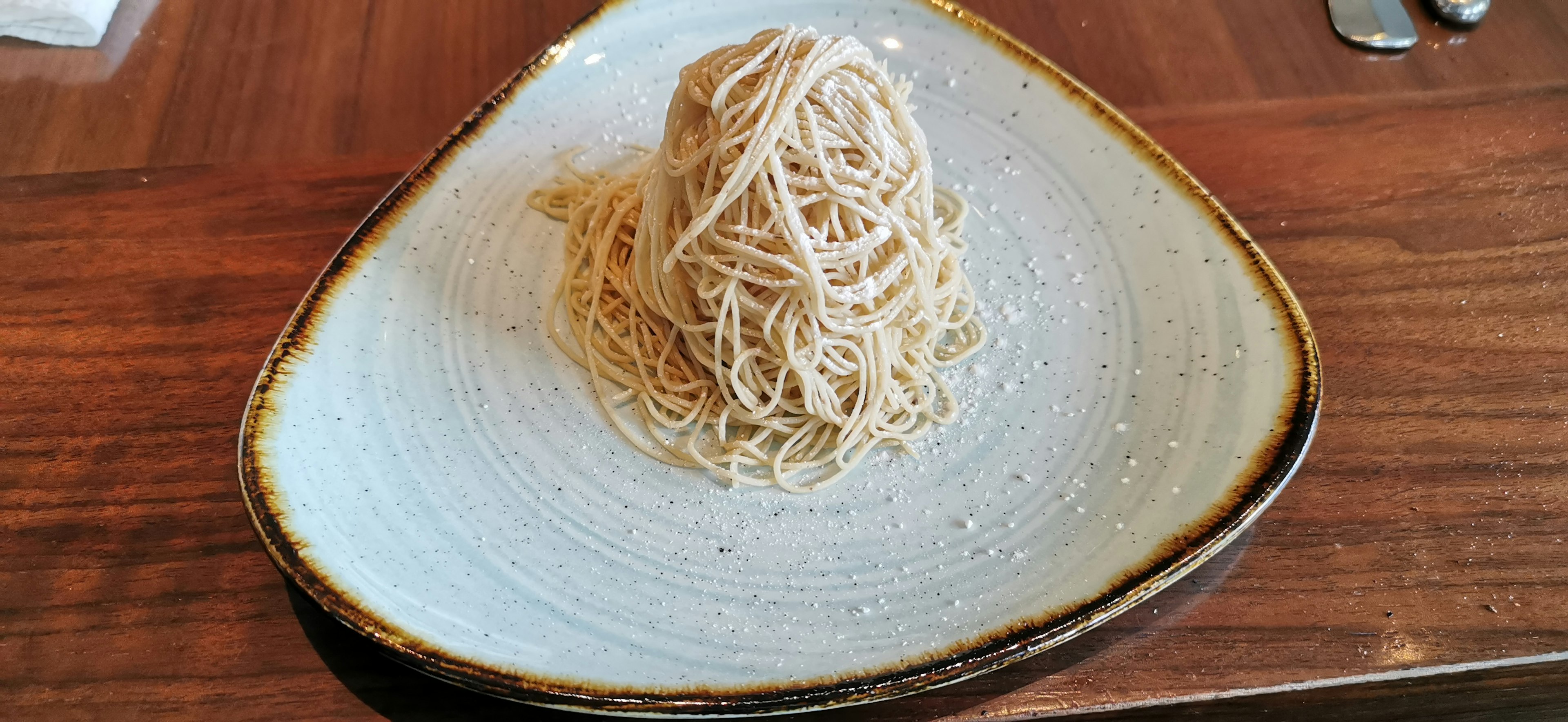 Ein Hügel aus dünner Pasta auf einem weißen Teller serviert