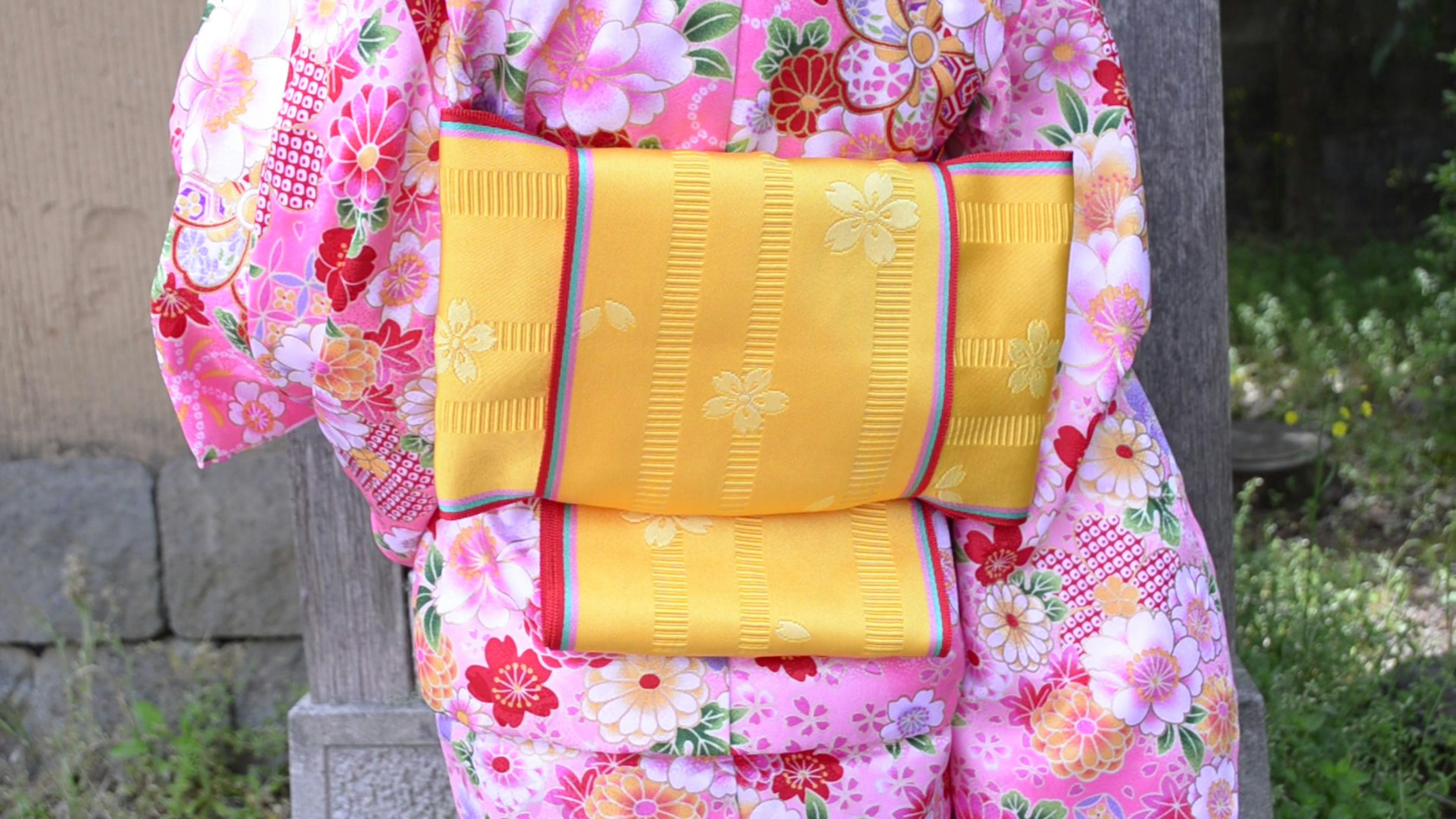 Persona que lleva un kimono floral vibrante con un obi amarillo