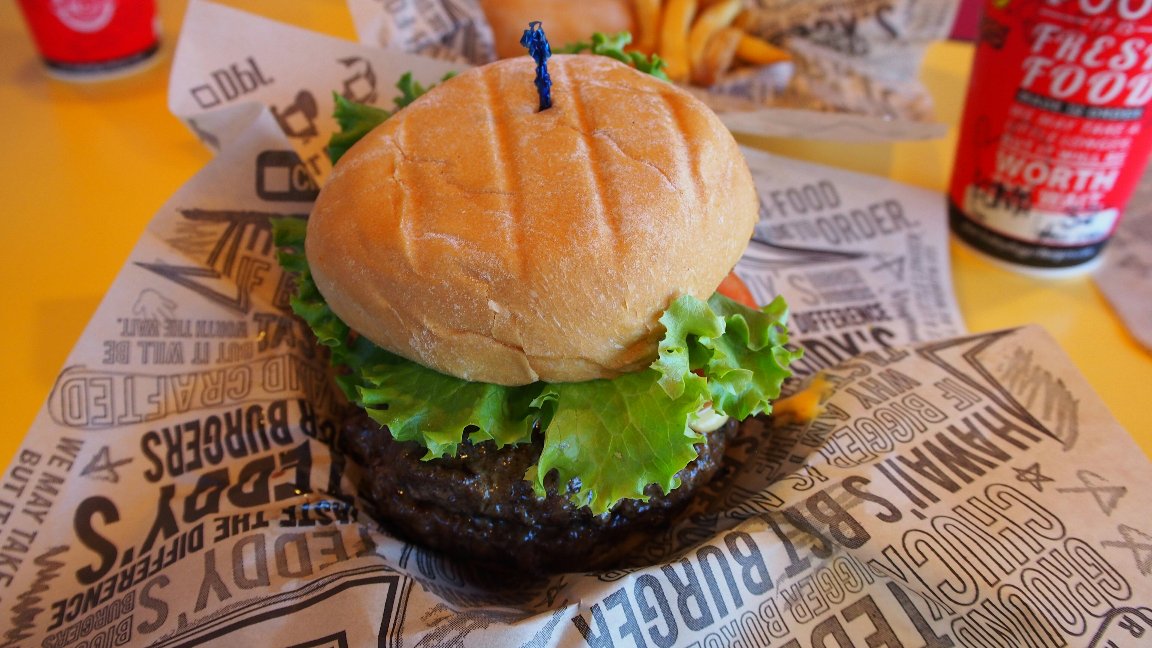 Piring dengan hamburger, selada segar dan roti lembut, disertai kentang goreng