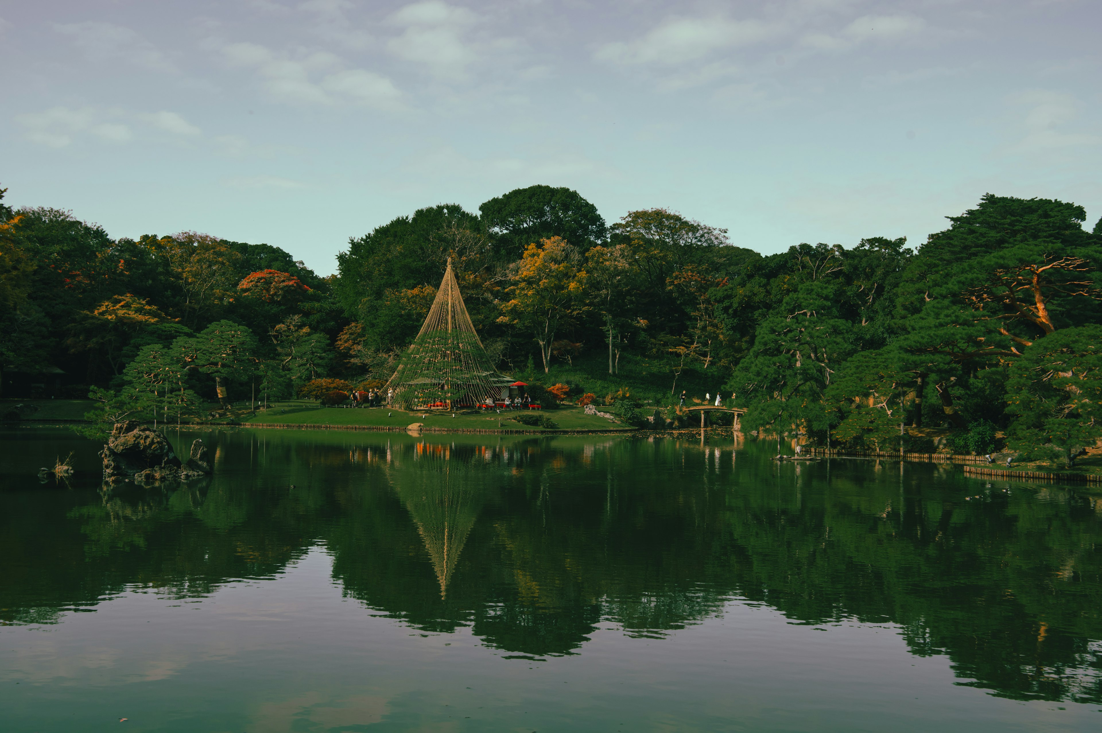 Scenic view of a hut by a tranquil lake surrounded by lush greenery