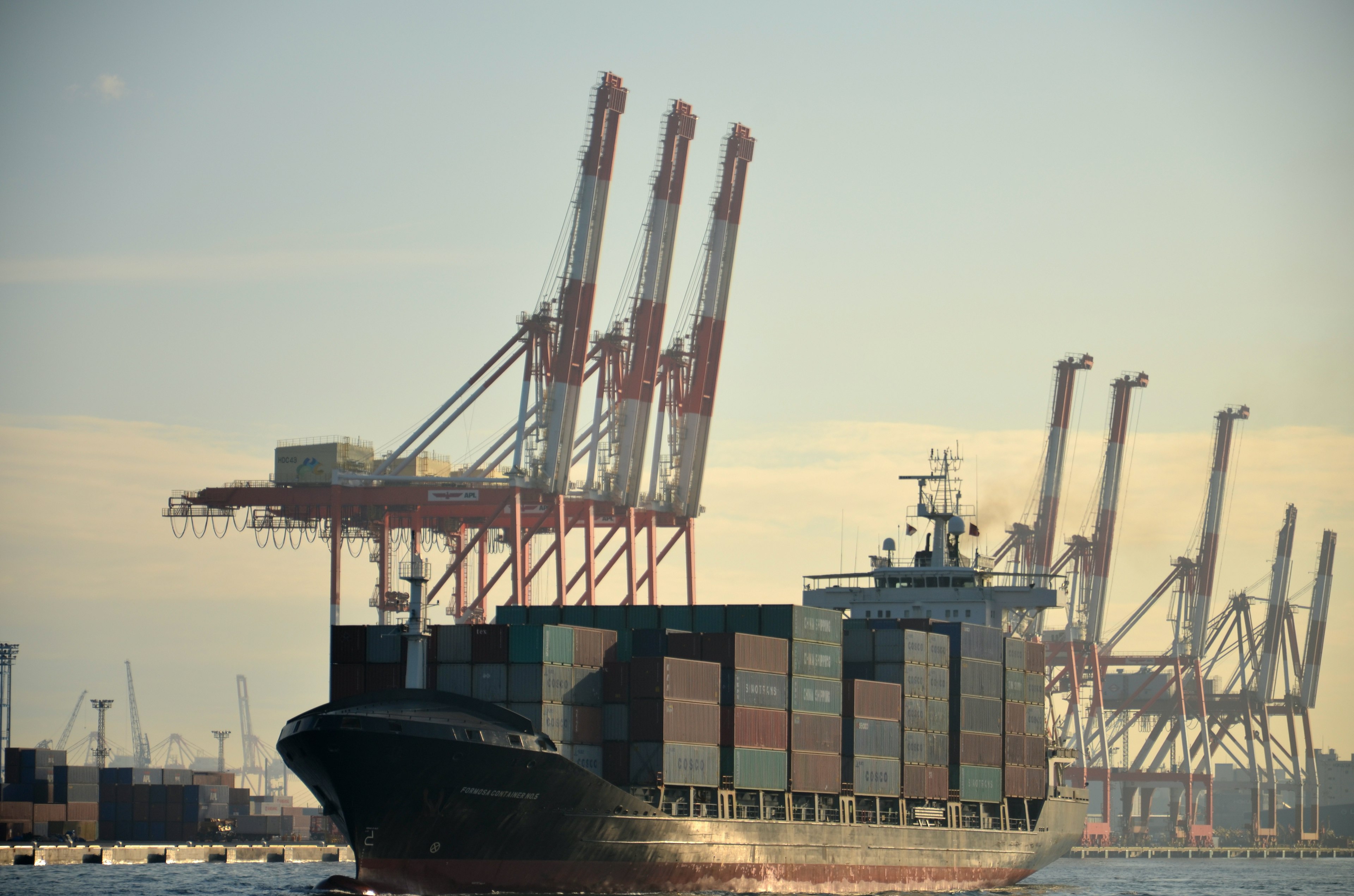 Navire de marchandises s'approchant du port avec des grues en arrière-plan