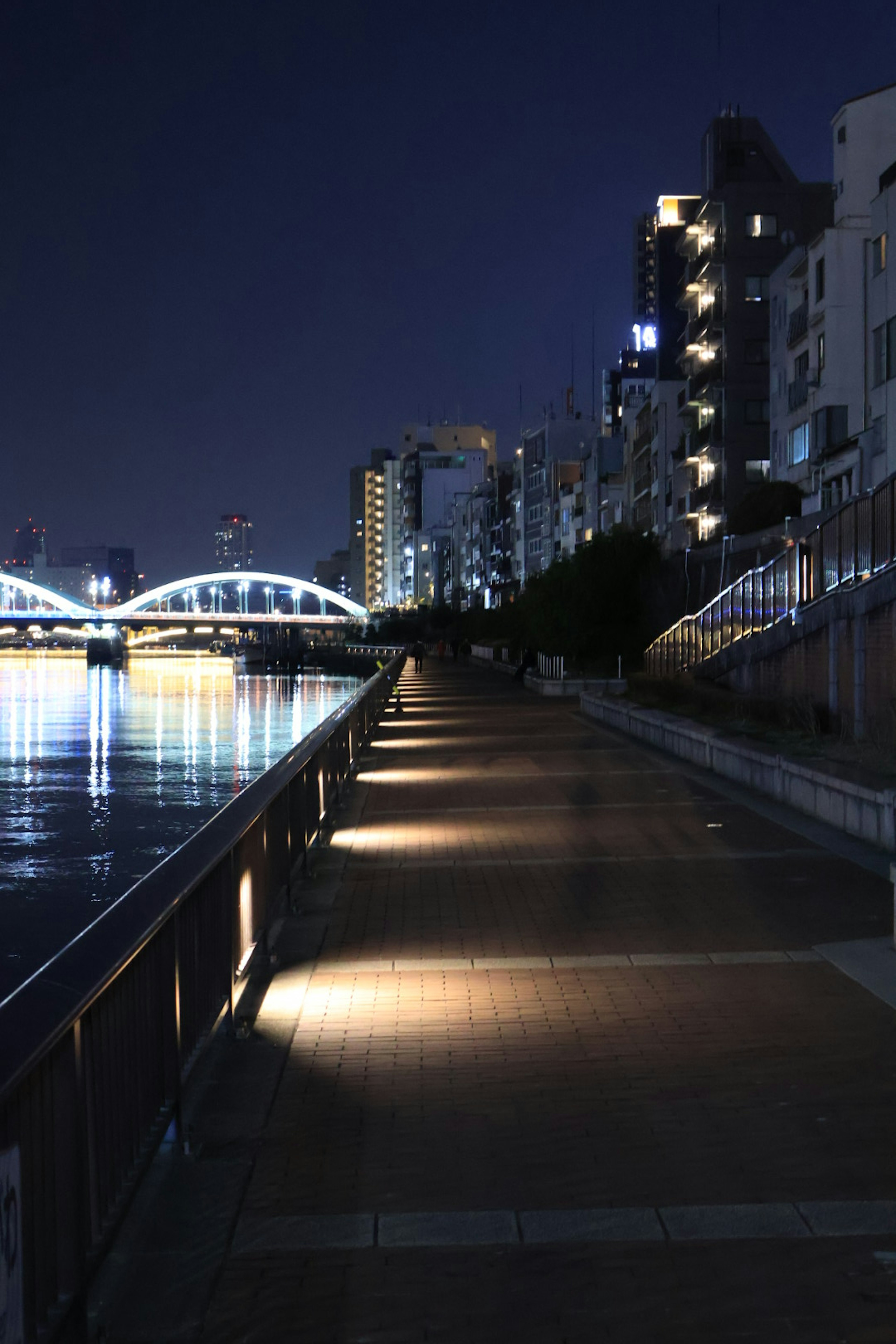 Caminata junto al río de noche con camino iluminado