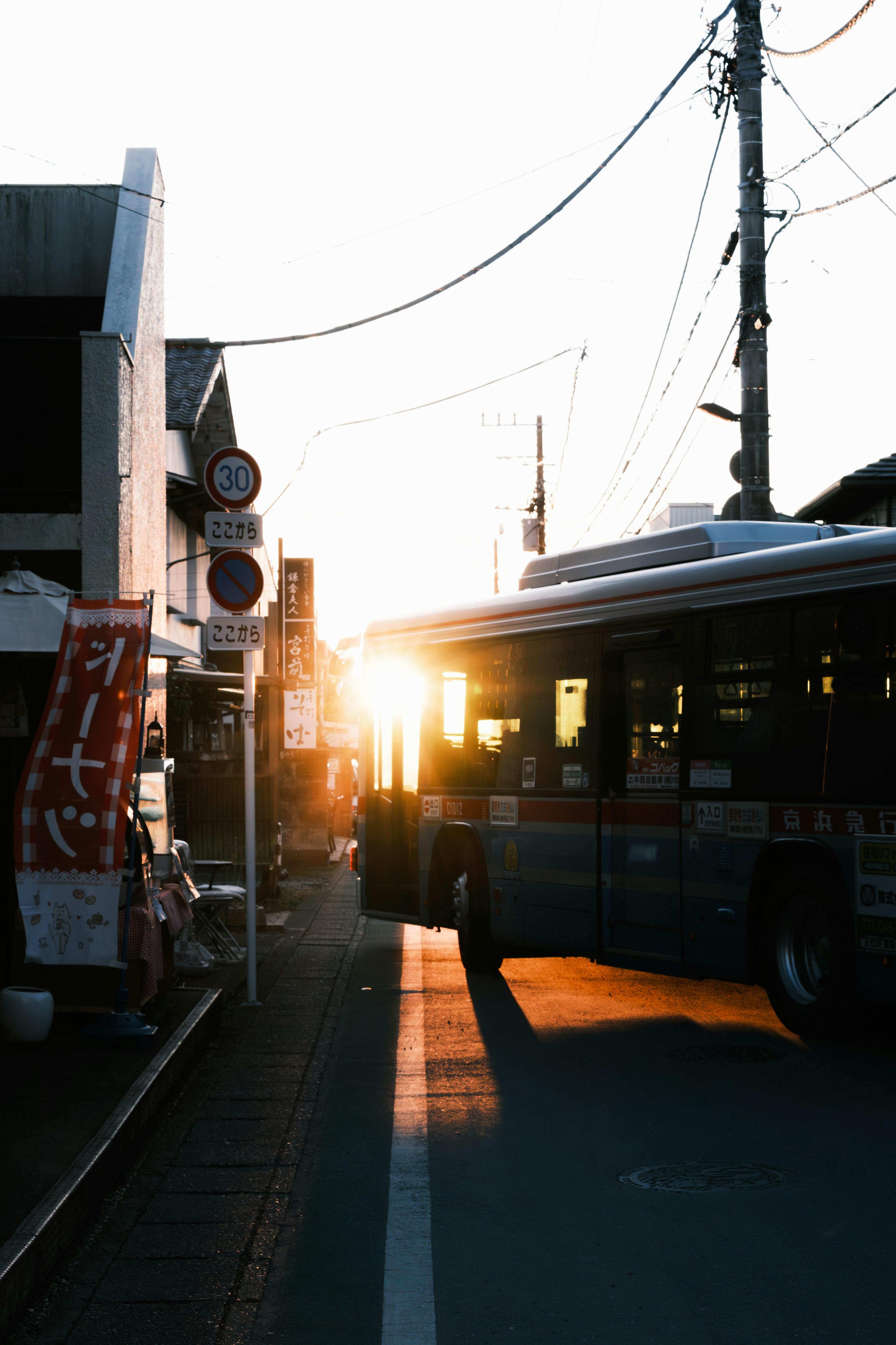 夕日が差し込む街角のバス停とバス