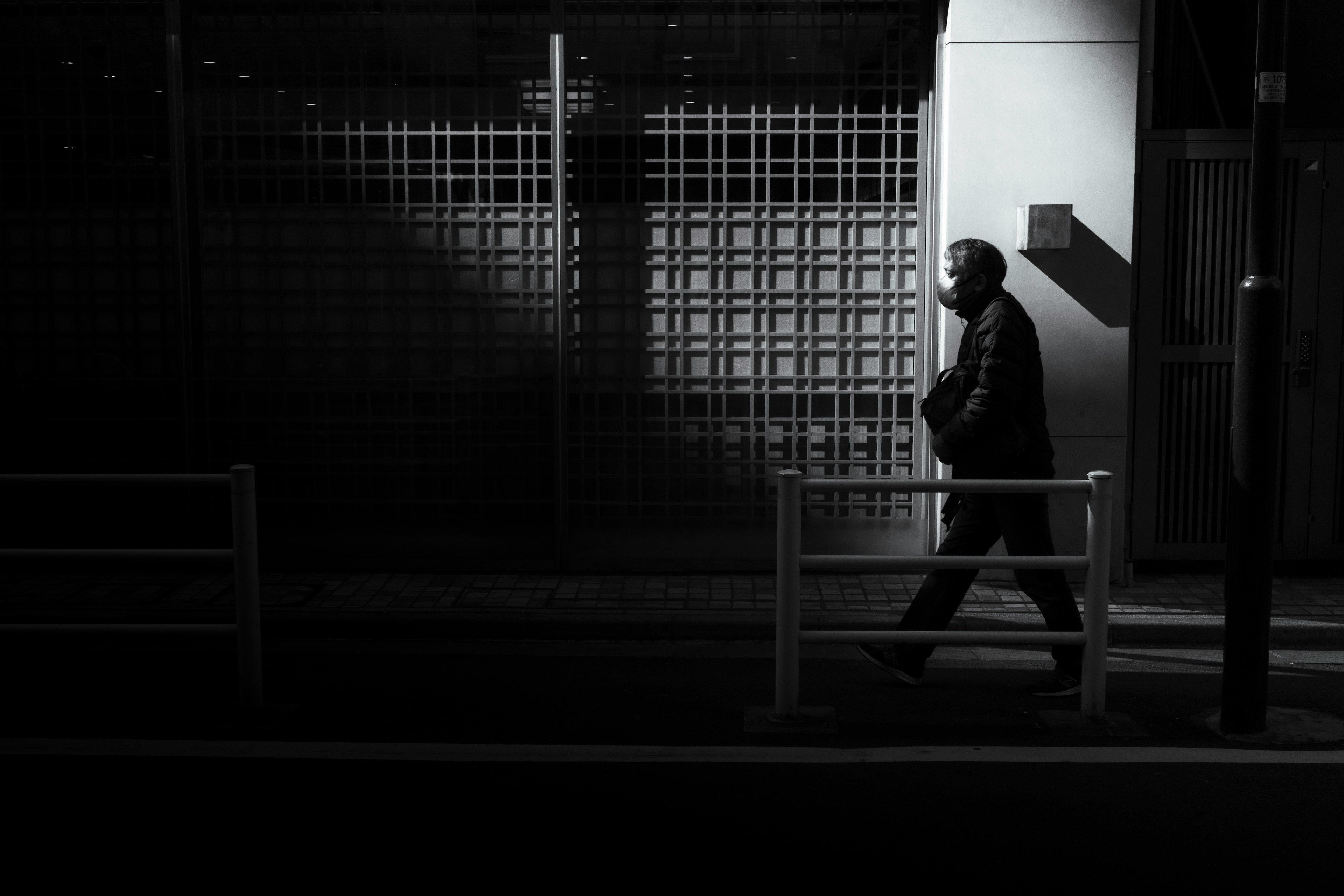 Silhouette d'un homme marchant dans la nuit avec des contrastes forts et des ombres