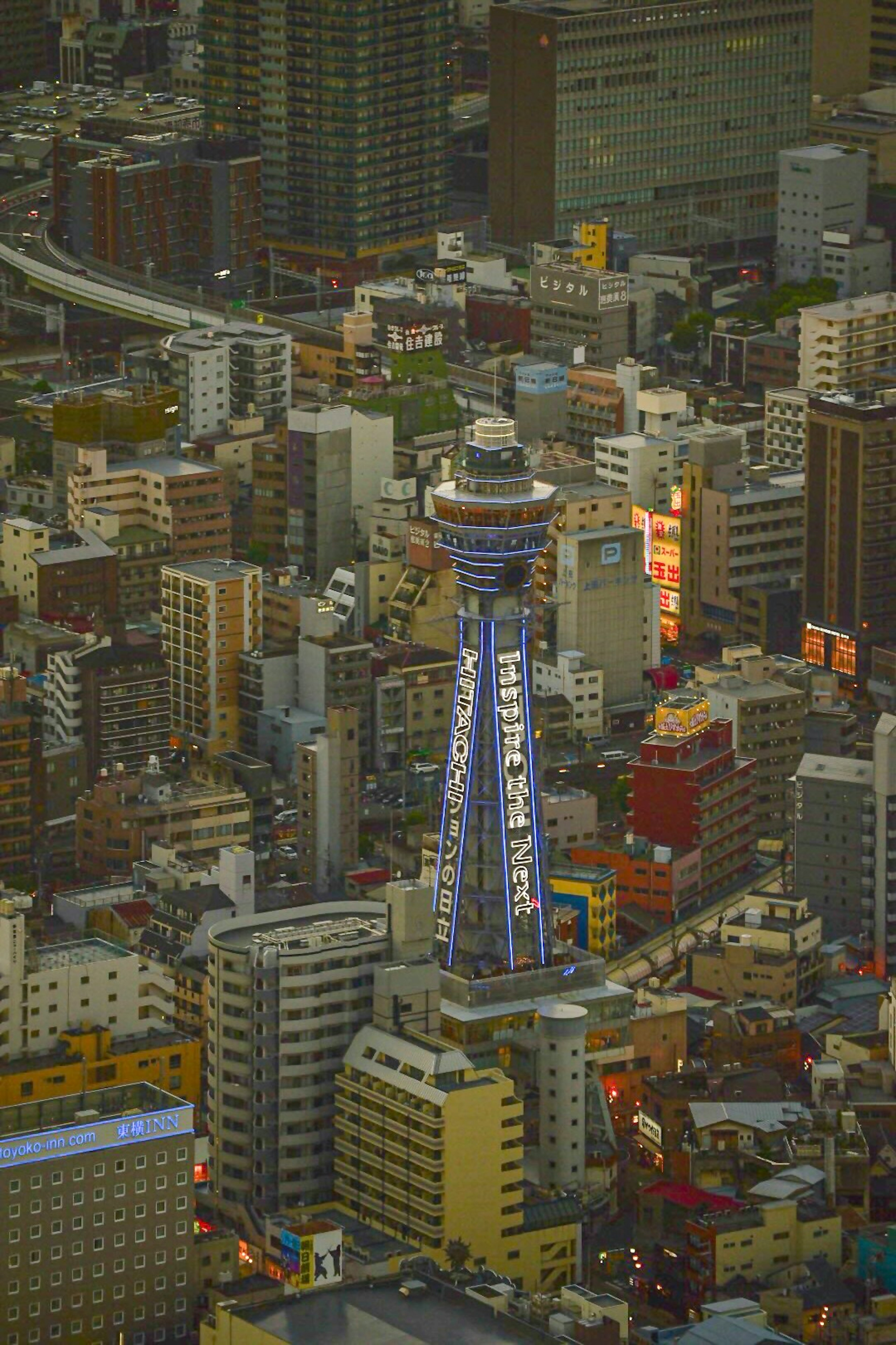 Vista nocturna de la Torre Tsutenkaku rodeada de rascacielos