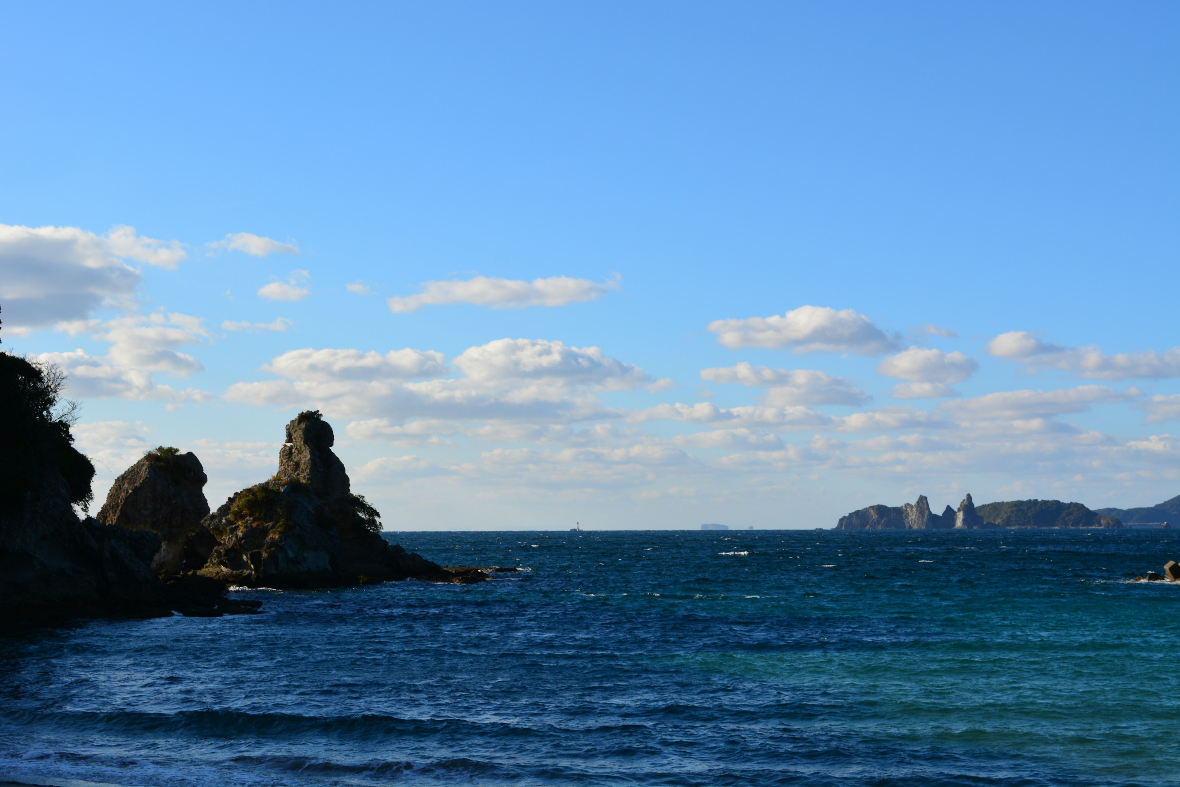 Coastal landscape with rocky formations and blue sea under a clear sky