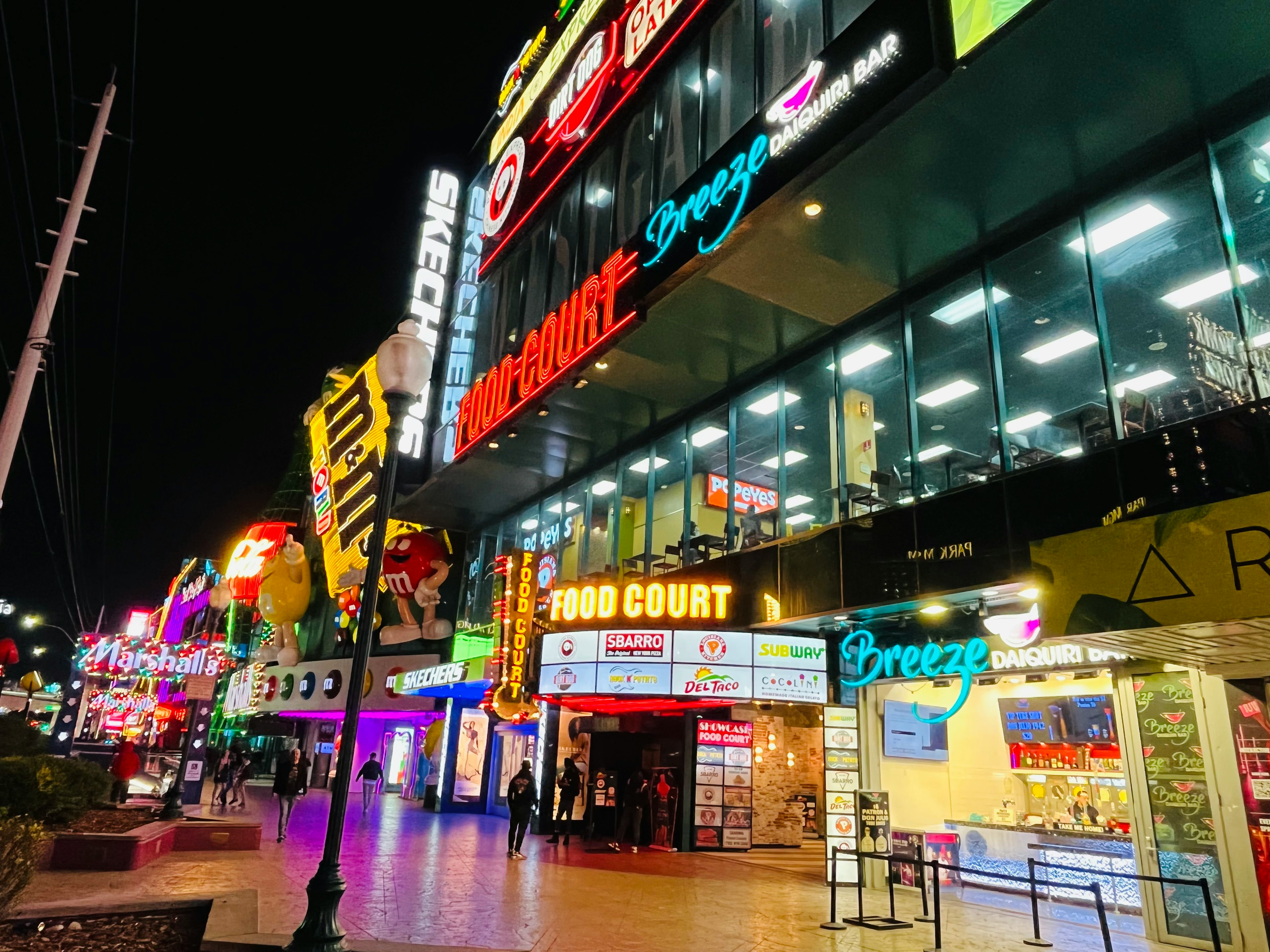 夜のフードコートとネオン看板が特徴的な繁華街の風景