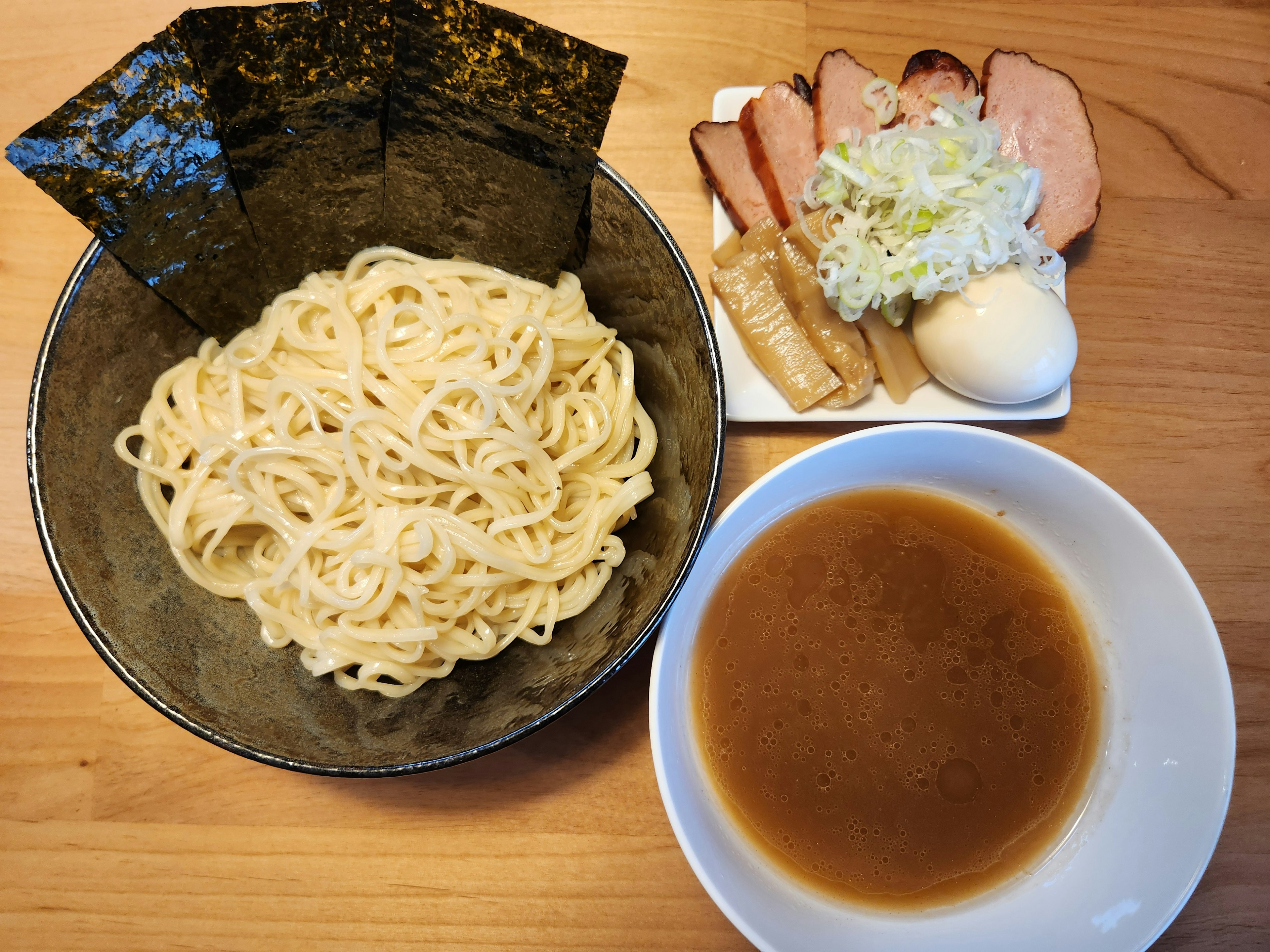 つけ麺の皿に盛られた太い麺とスープのボウル サイドにトッピングのチャーシューとキャベツ