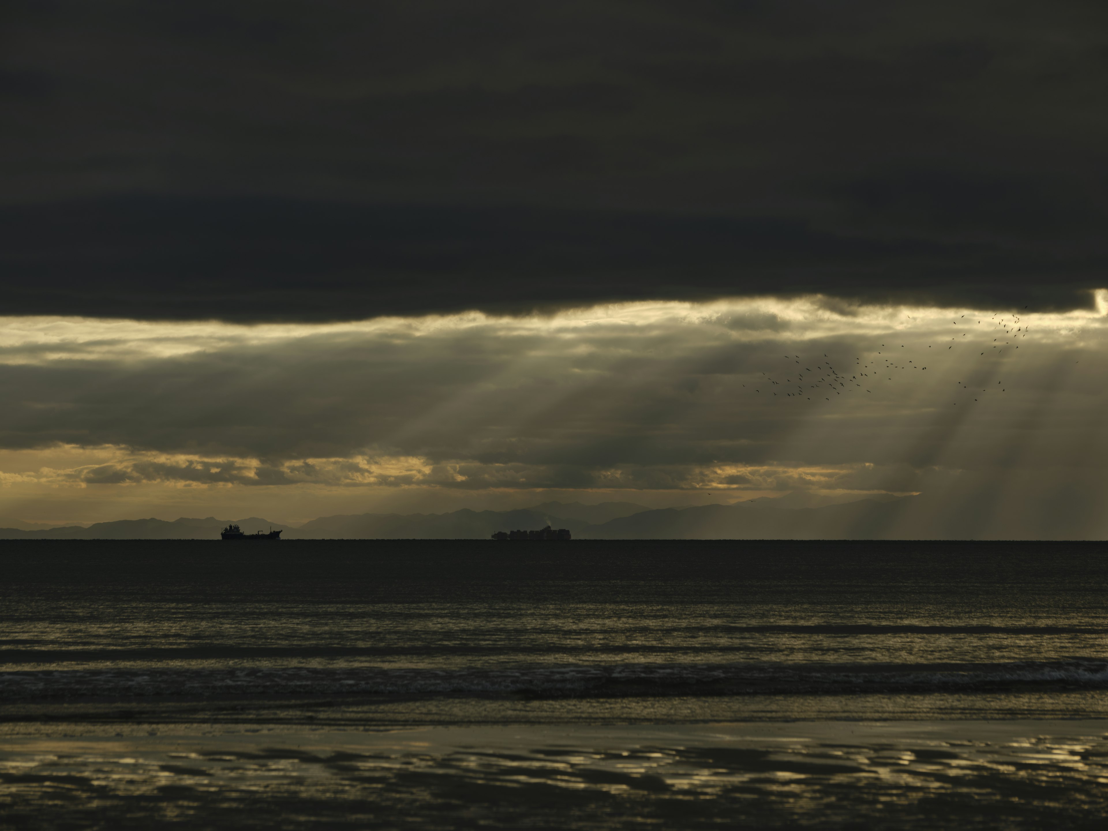 Dark ocean scene with rays of light breaking through clouds