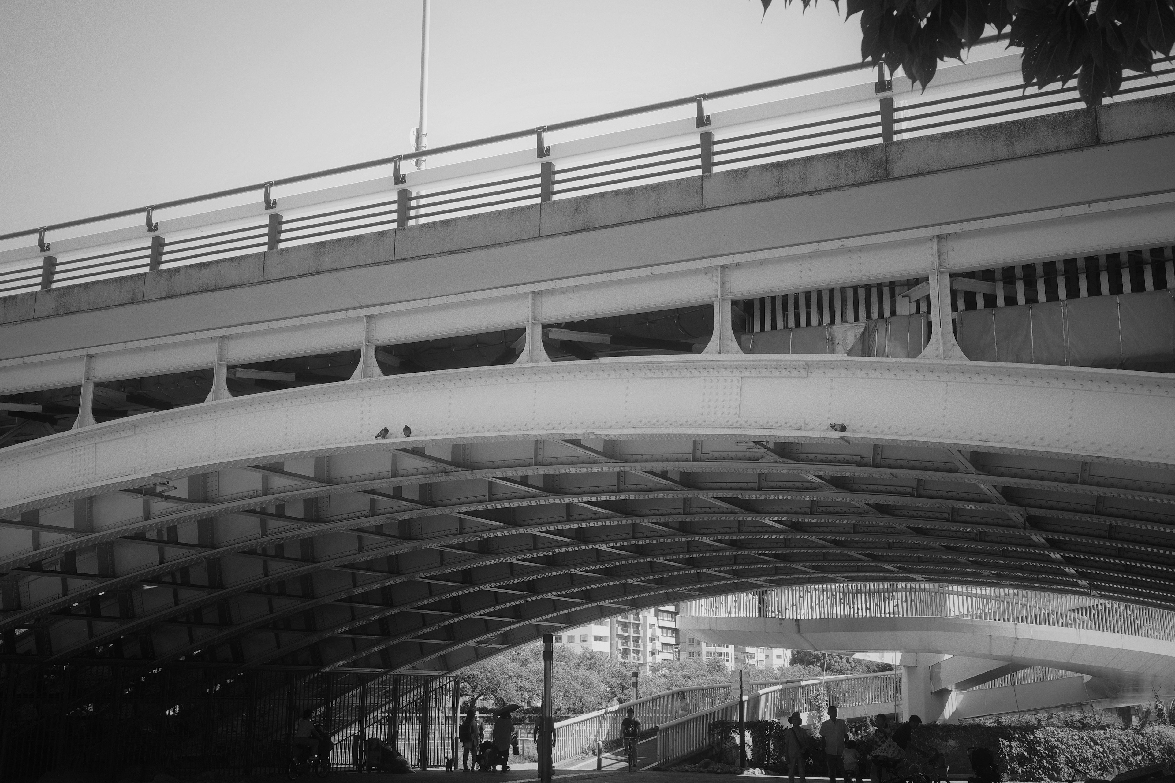 People walking under a modern arch bridge