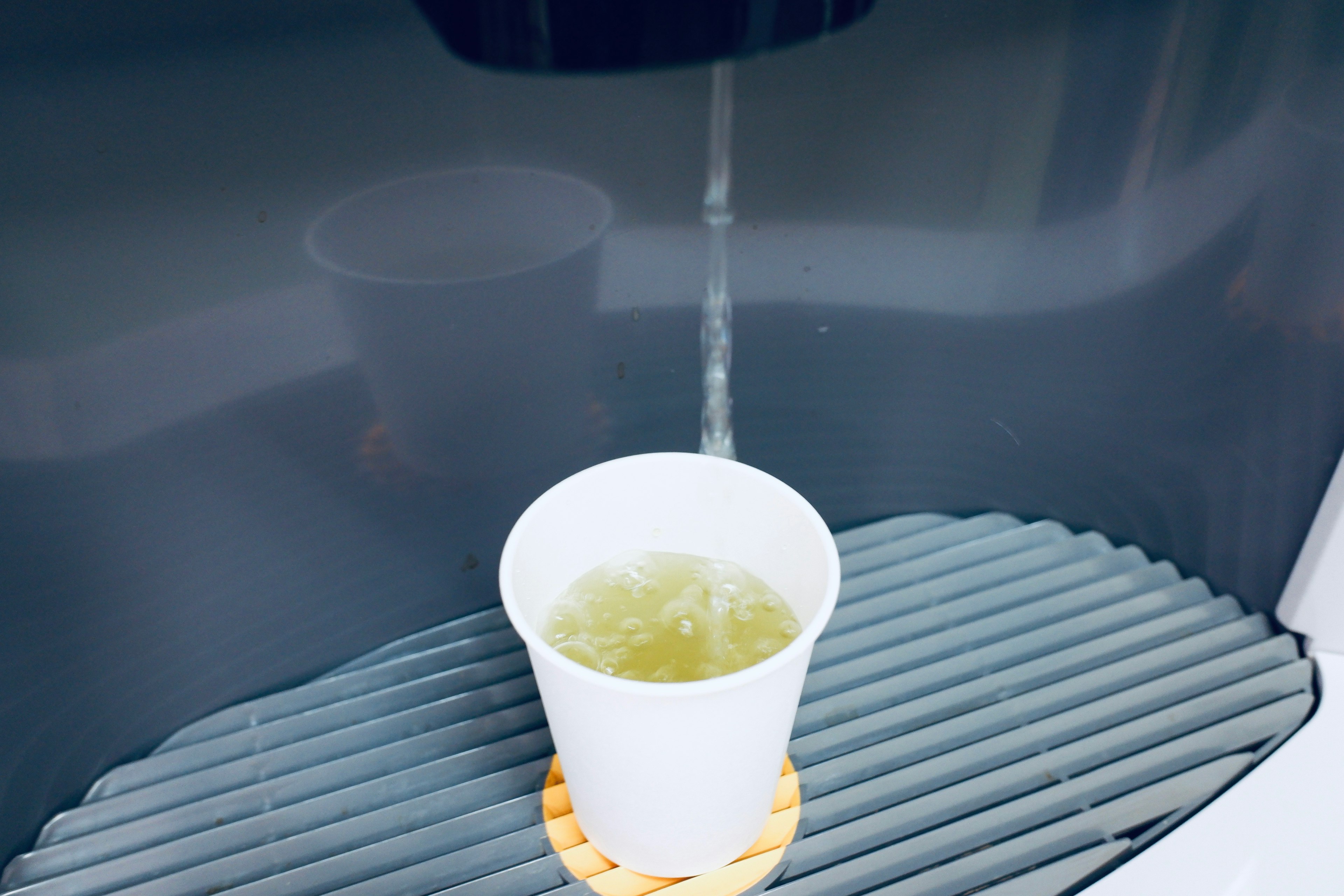 Image of a drink being poured into a white paper cup