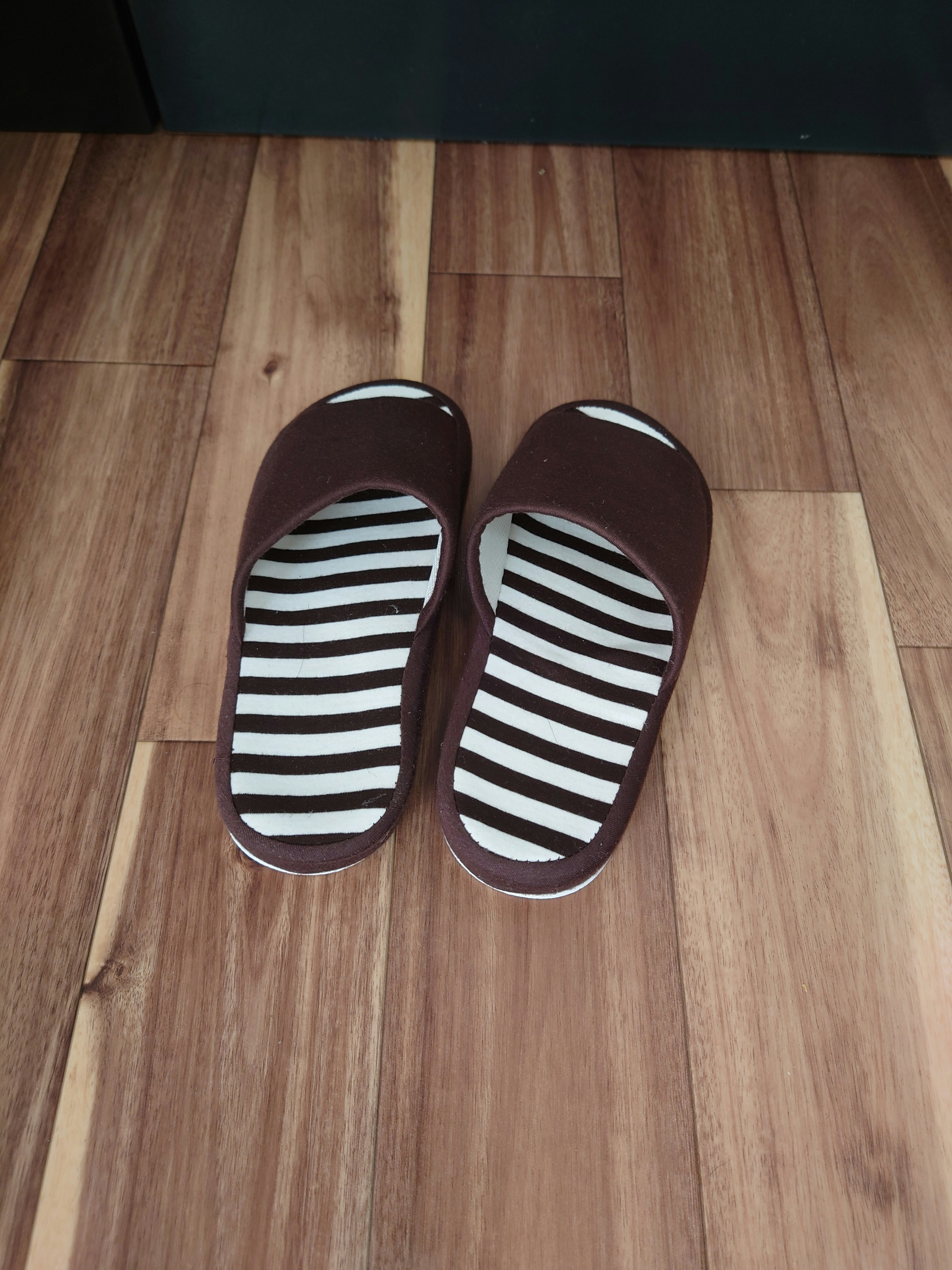 Brown slippers placed on wooden flooring