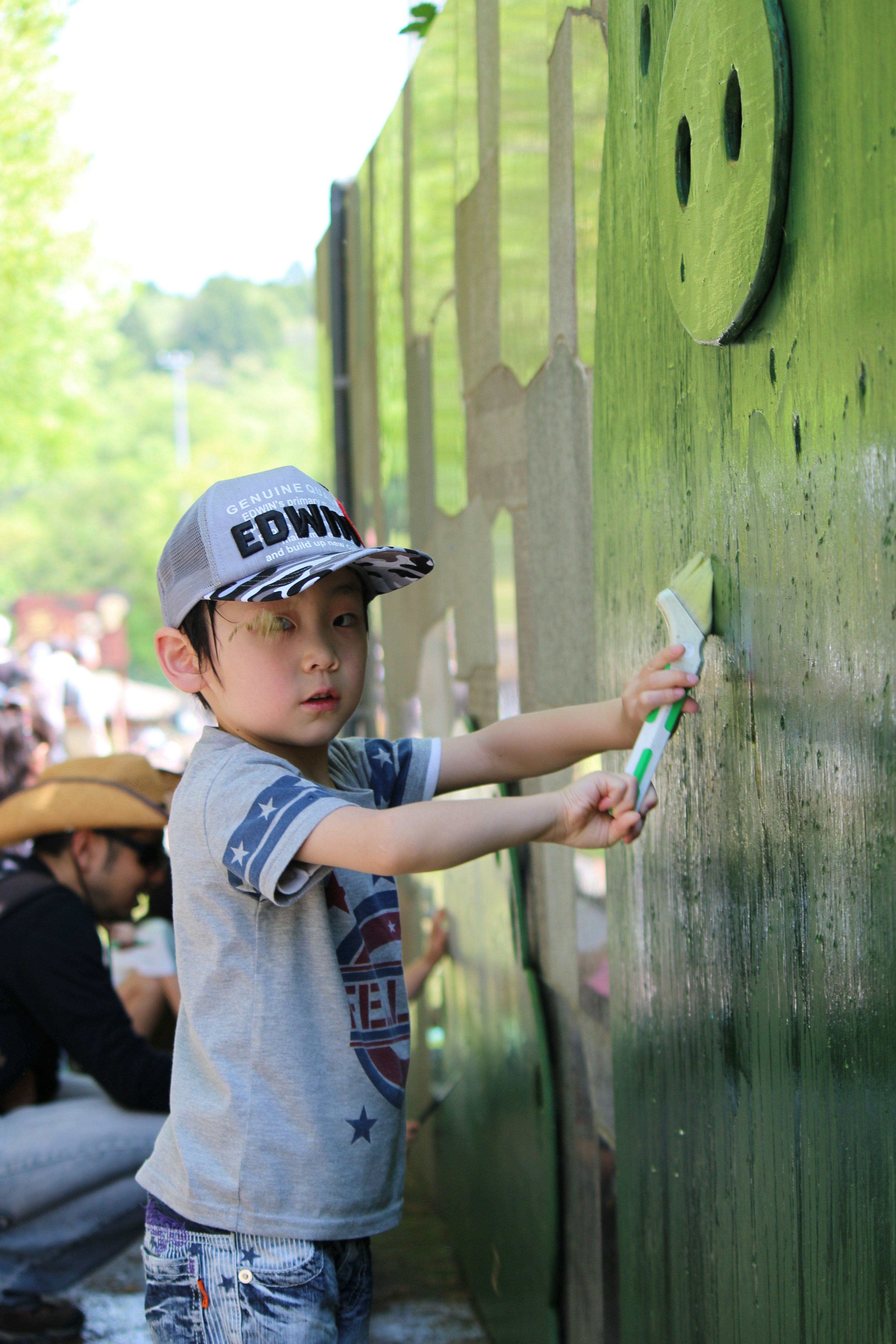 Un niño pintando una pared verde con una gorra