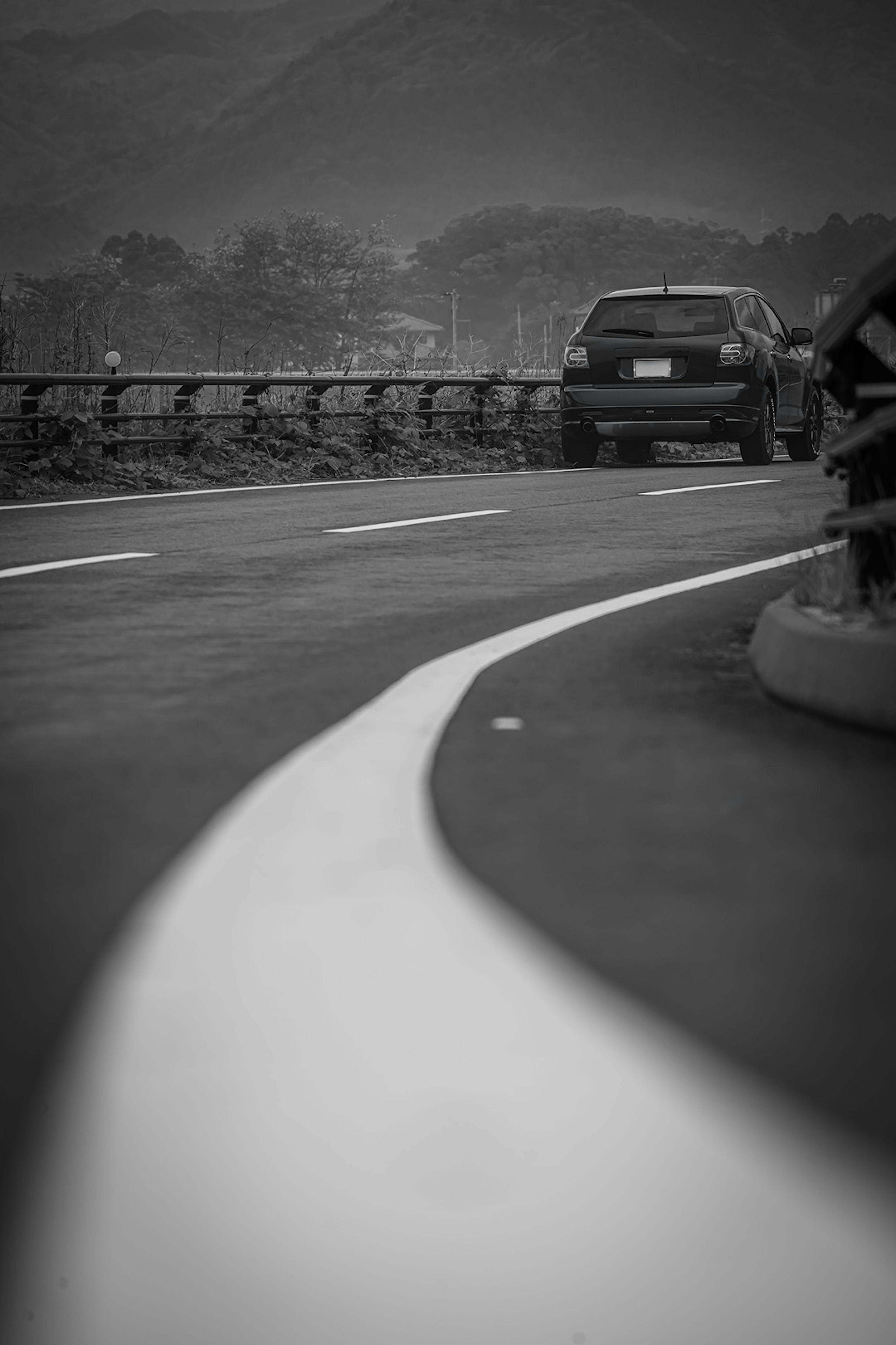 白い曲線の道路と黒い車が映る風景