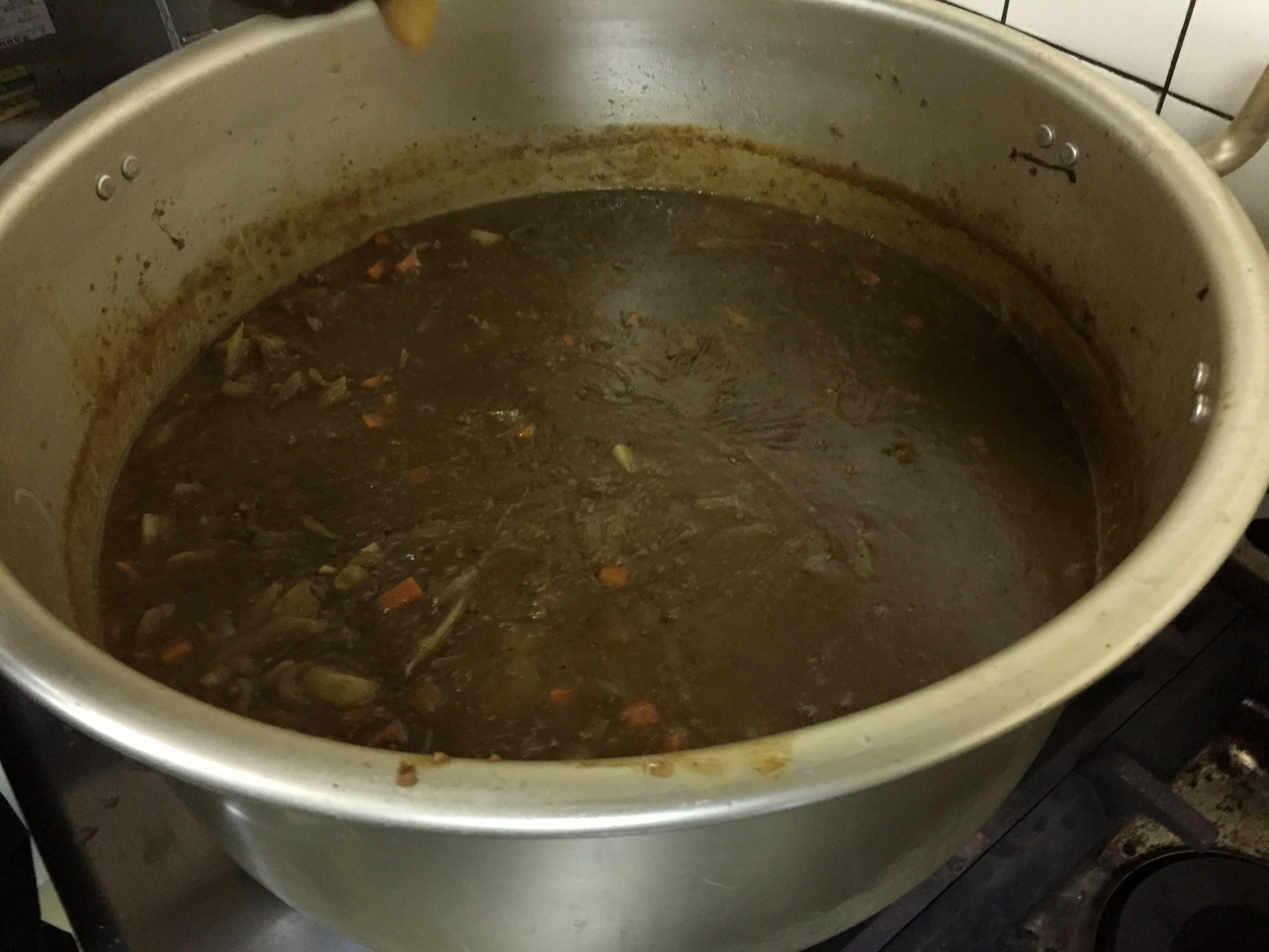 Large pot filled with dark soup and vegetables