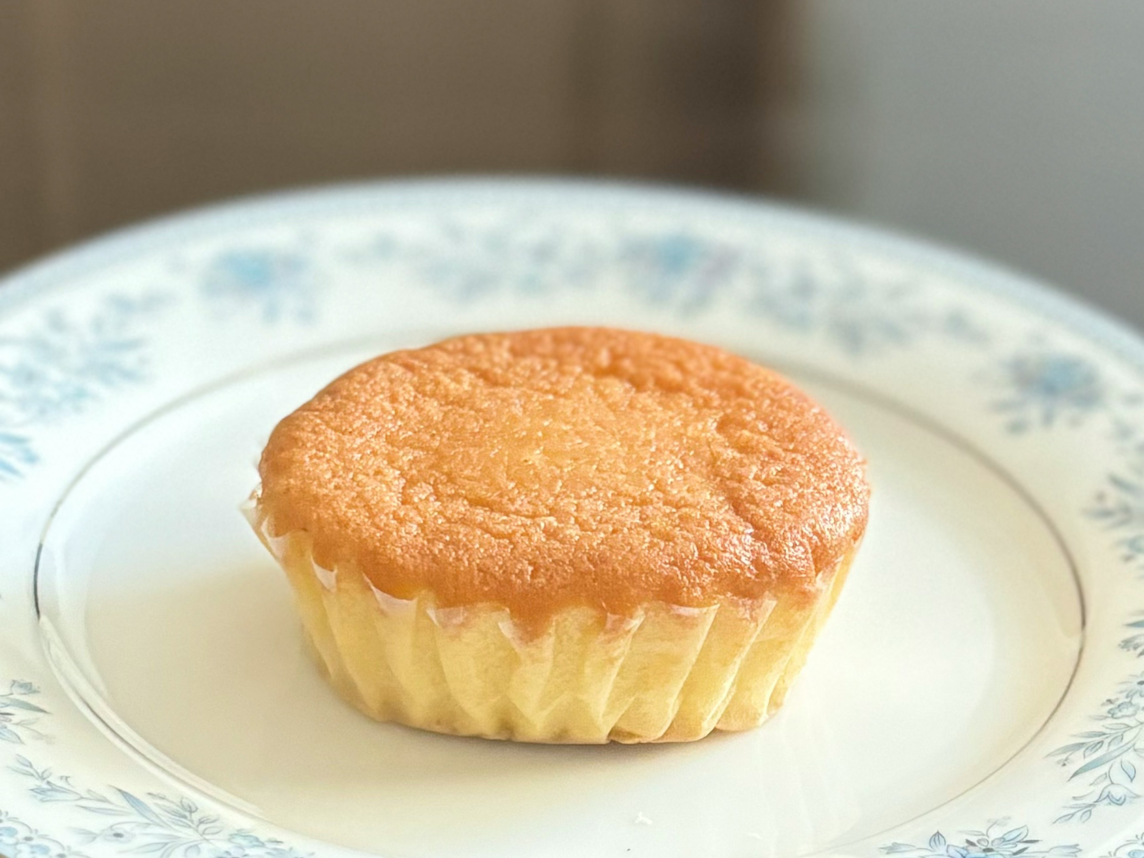 Muffin dorado en un plato blanco con diseño floral azul