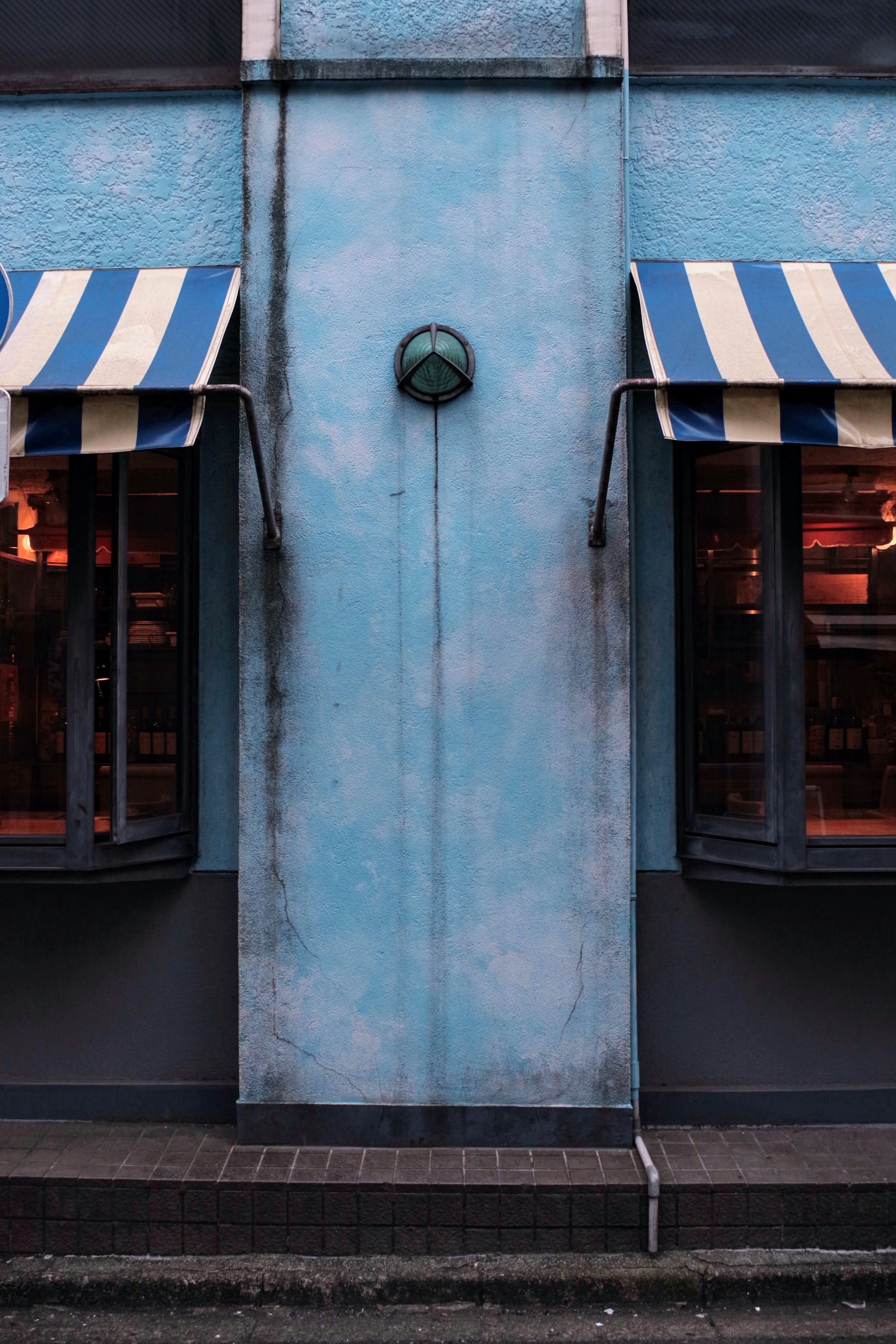 Extérieur d'un bâtiment avec un mur bleu et des auvents rayés