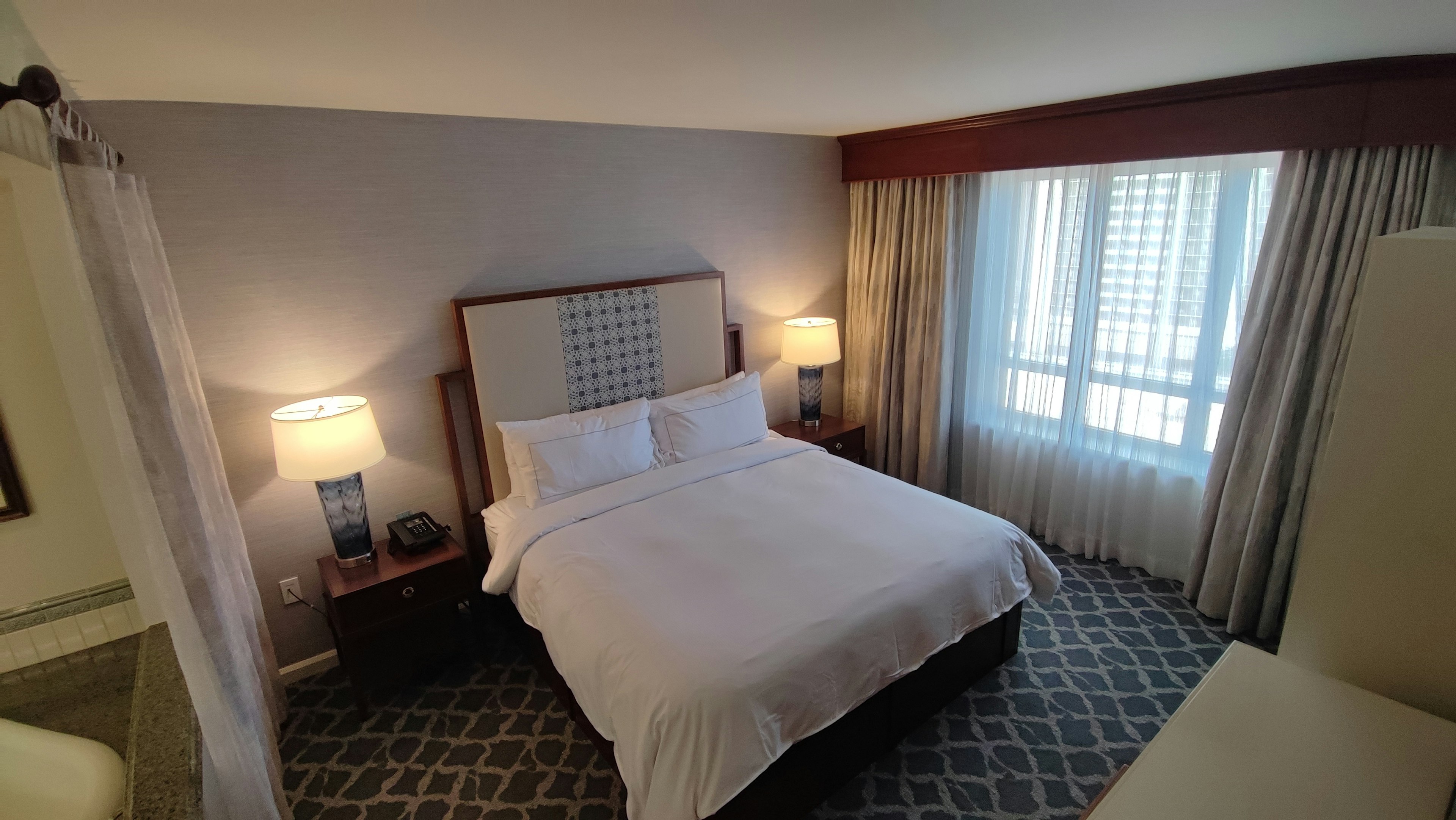 Brightly lit hotel room featuring a double bed and large window