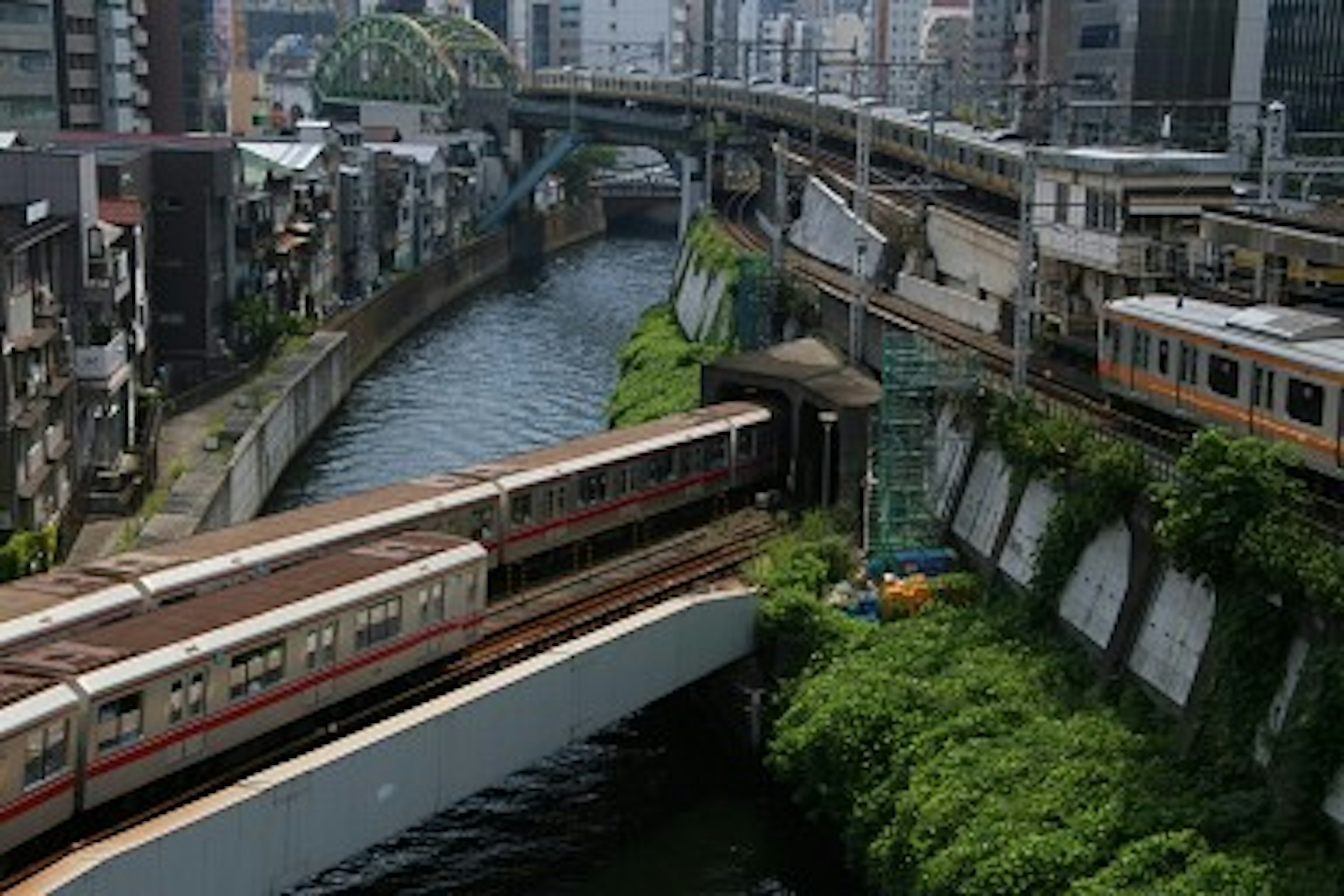 Paysage urbain avec une rivière et un chemin de fer qui se croisent rives verdoyantes et voies ferrées surélevées