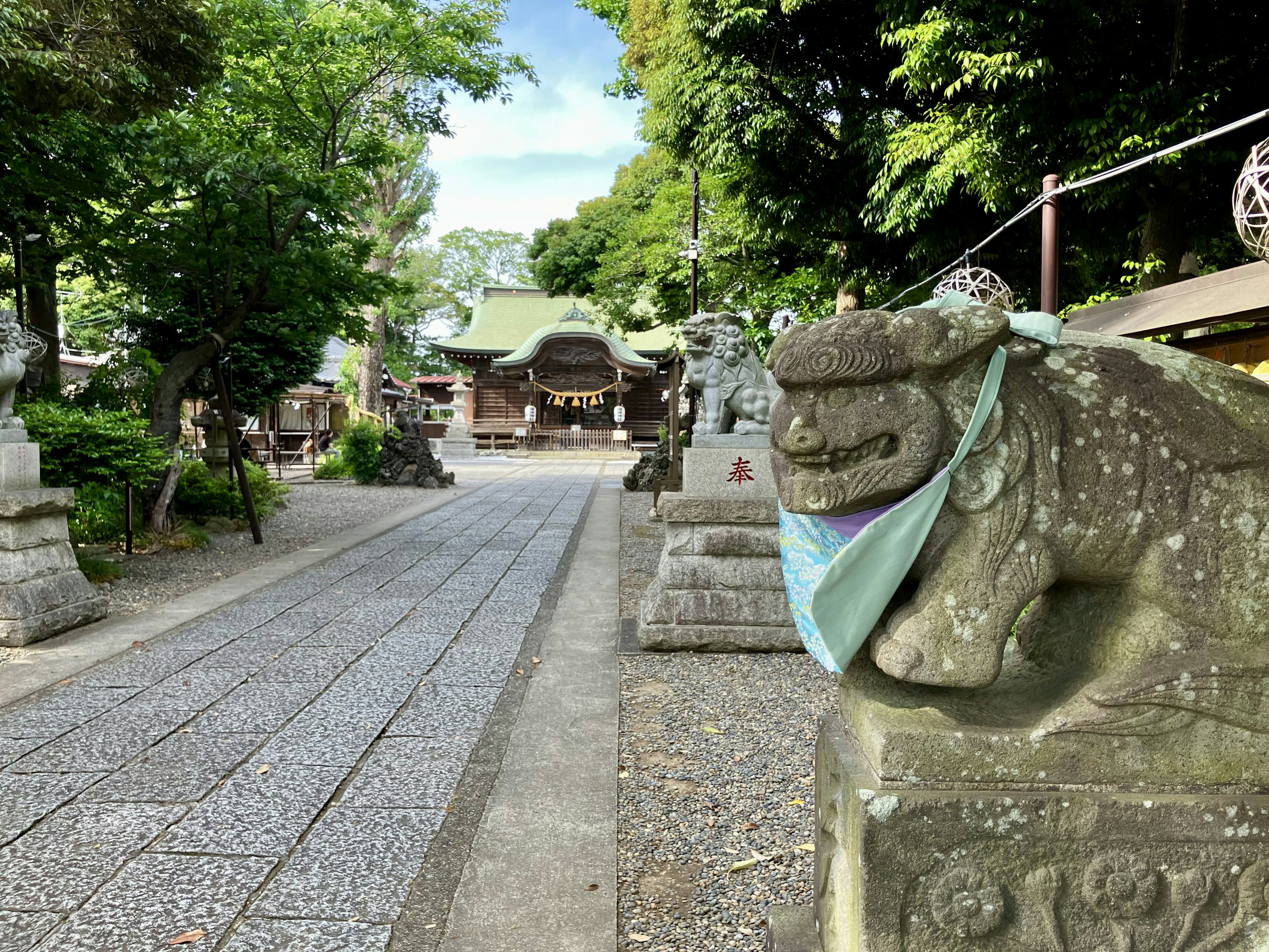 Stone guardian lion statue wearing a mask at a shrine path