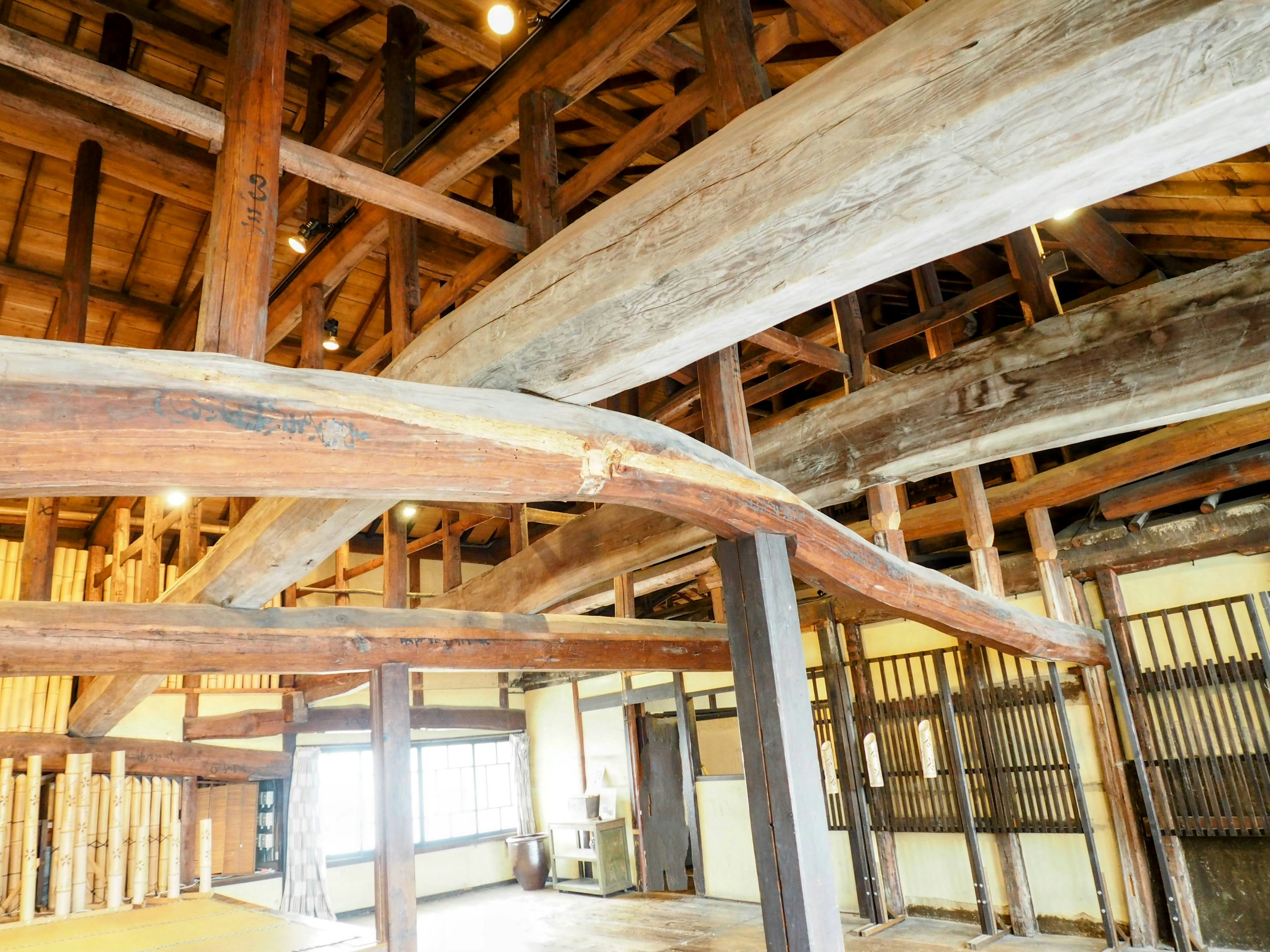 Interior dari struktur kayu tradisional dengan balok tebal dan cahaya alami