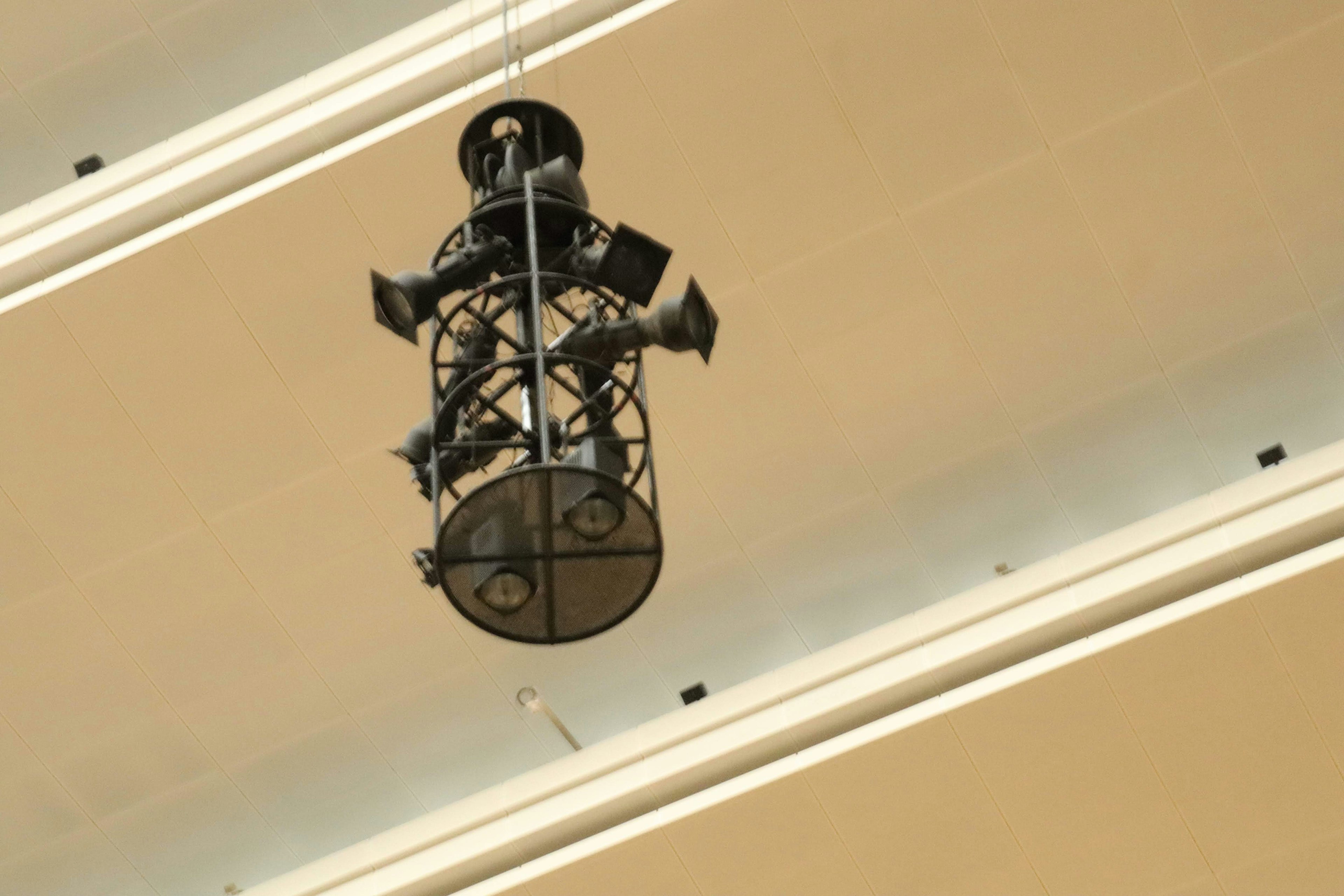 Black speaker and lighting fixture hanging from the ceiling