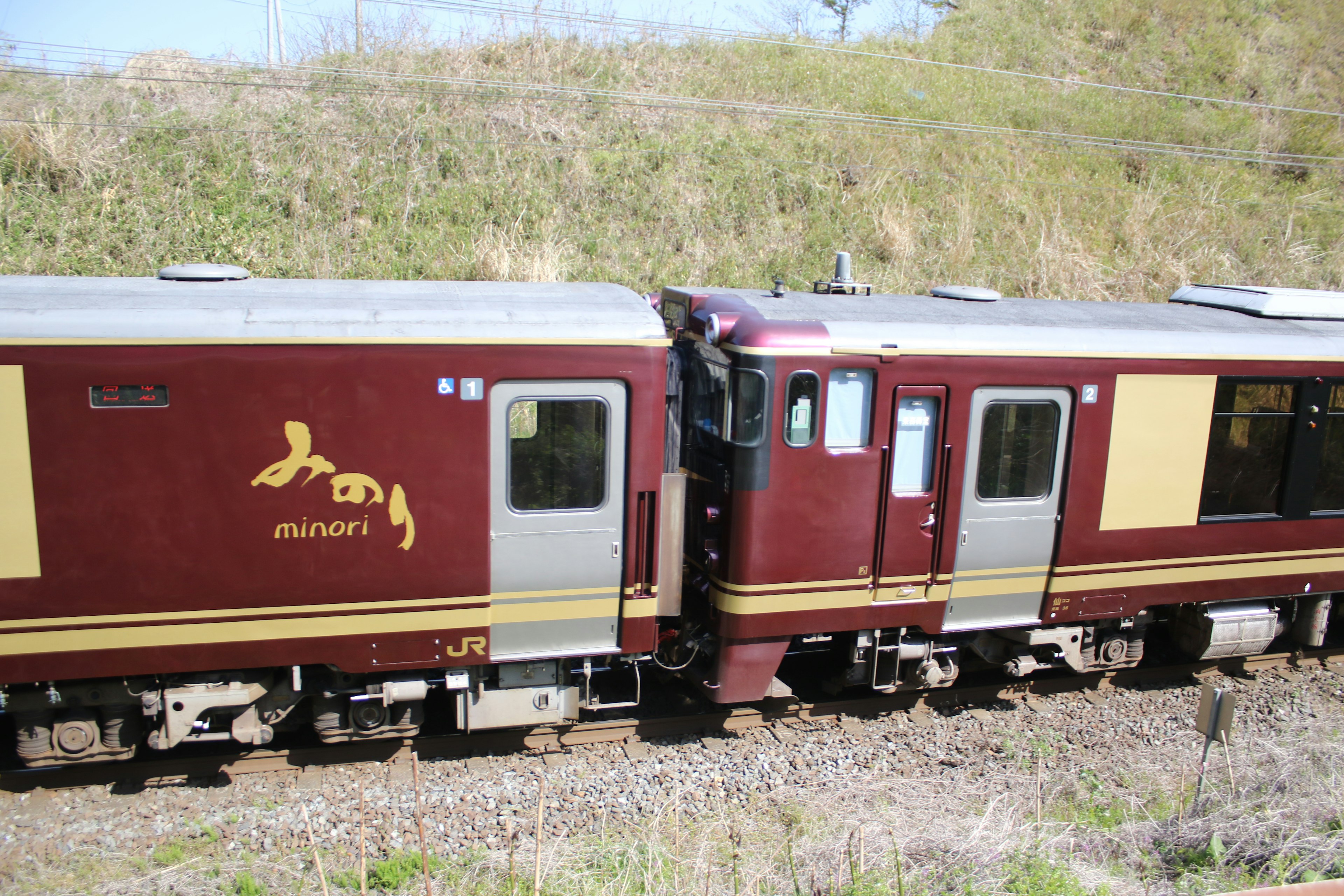 Maroon and cream train cars connected on a sunny day