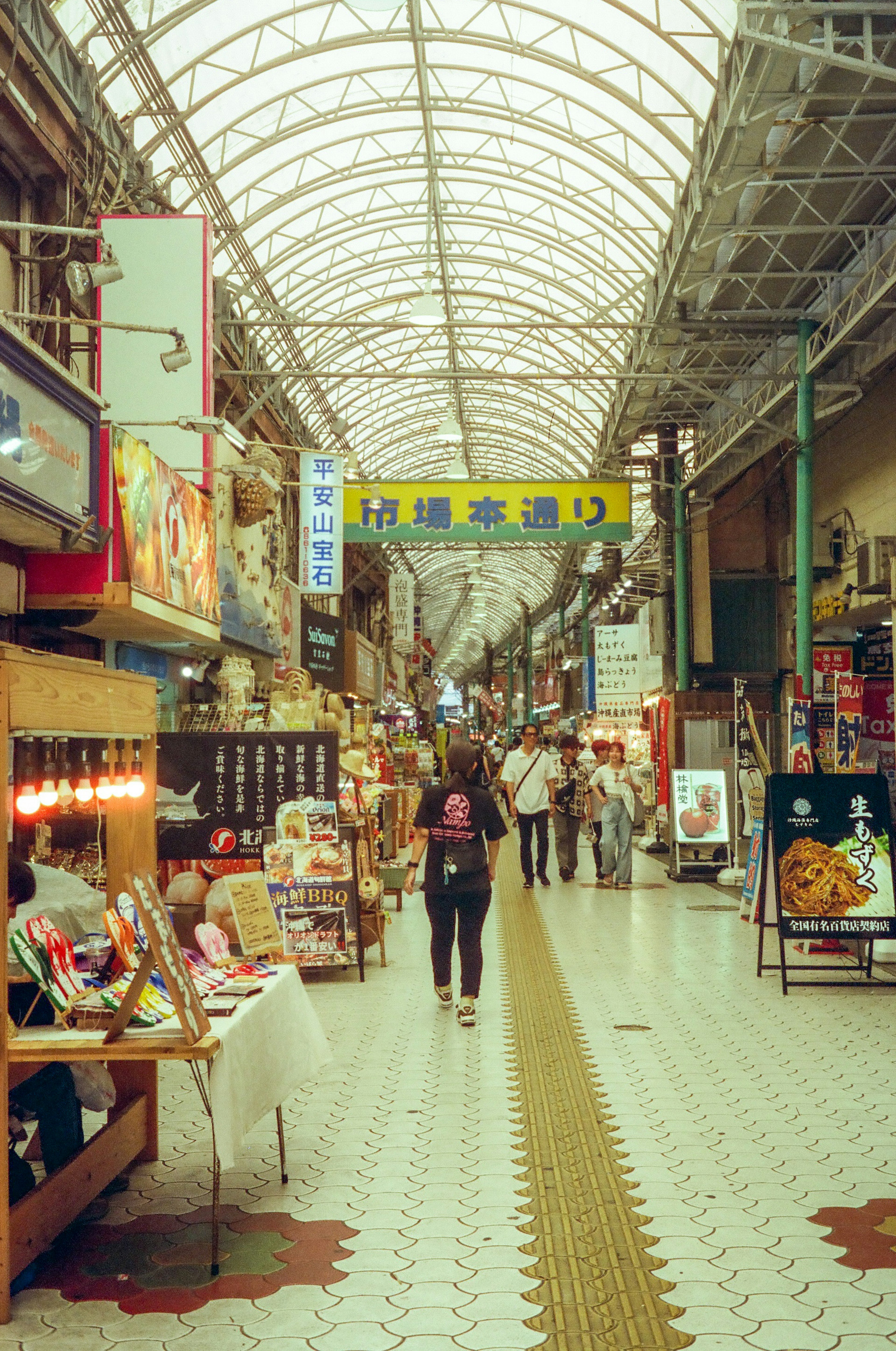 A bustling covered shopping arcade with people walking and various shops lining the sides