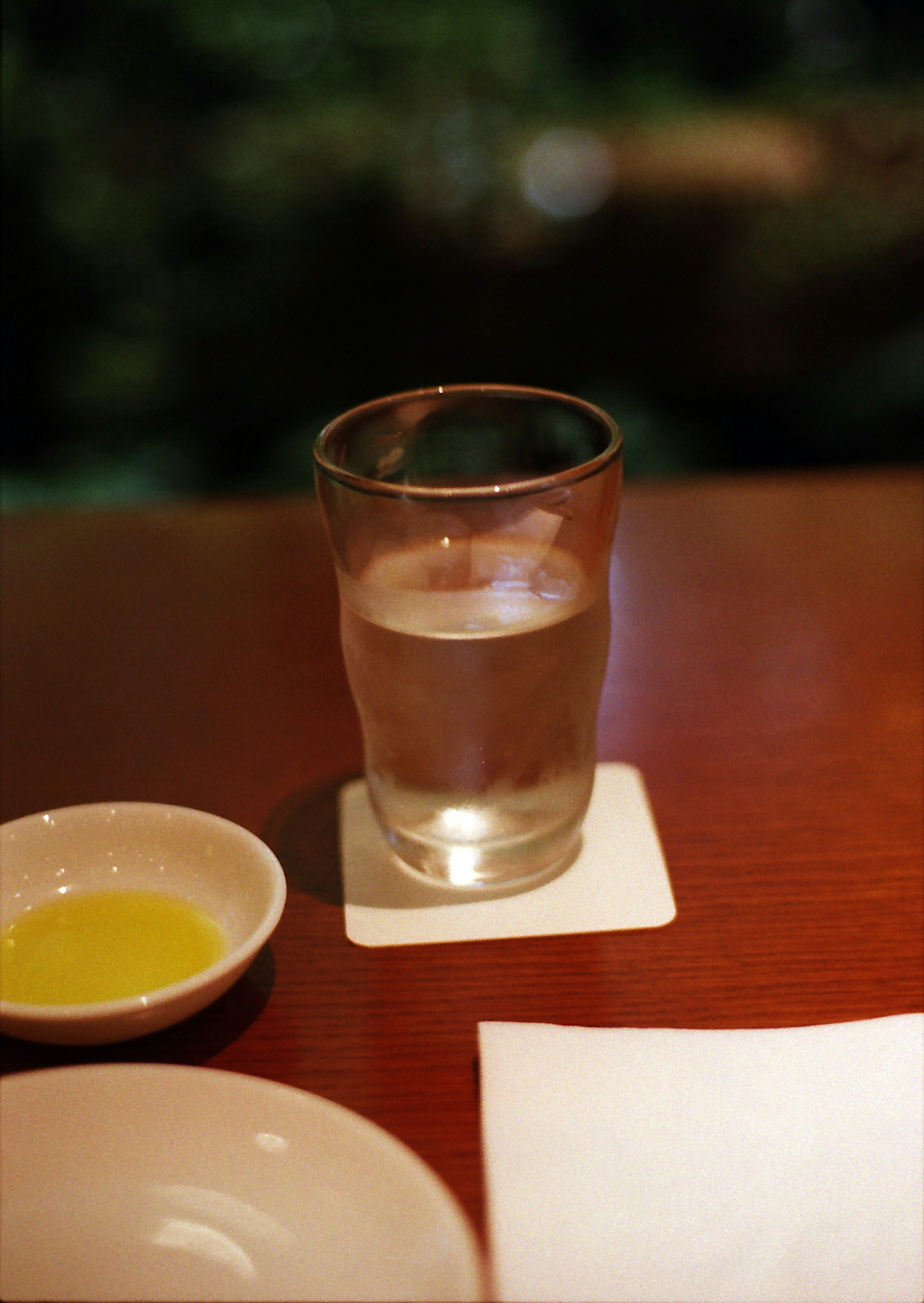 Un vaso de agua en una mesa con un pequeño plato de aceite de oliva