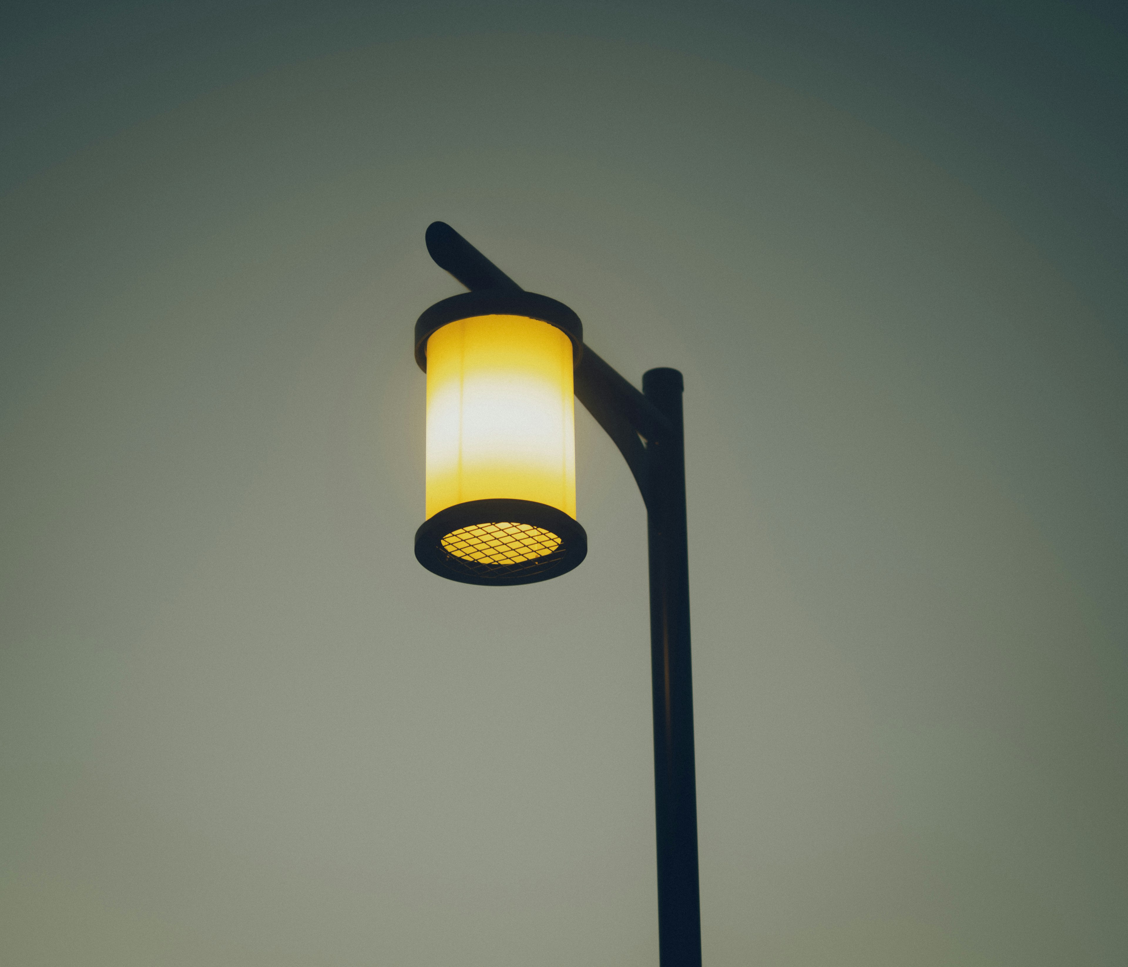 A street lamp with a yellow glowing lamp design atop a pole