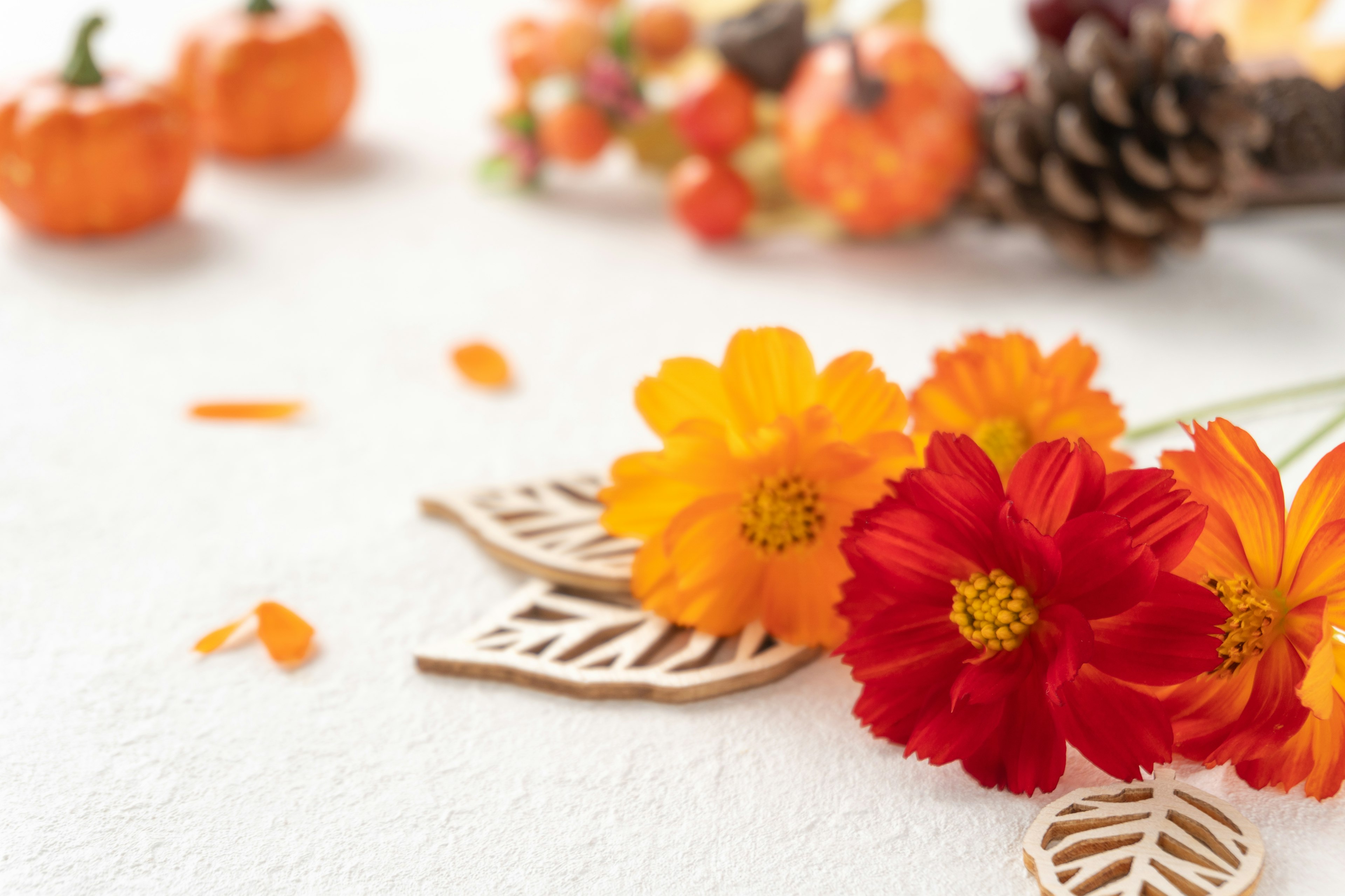 Arreglo de flores naranjas y rojas con decoraciones de otoño